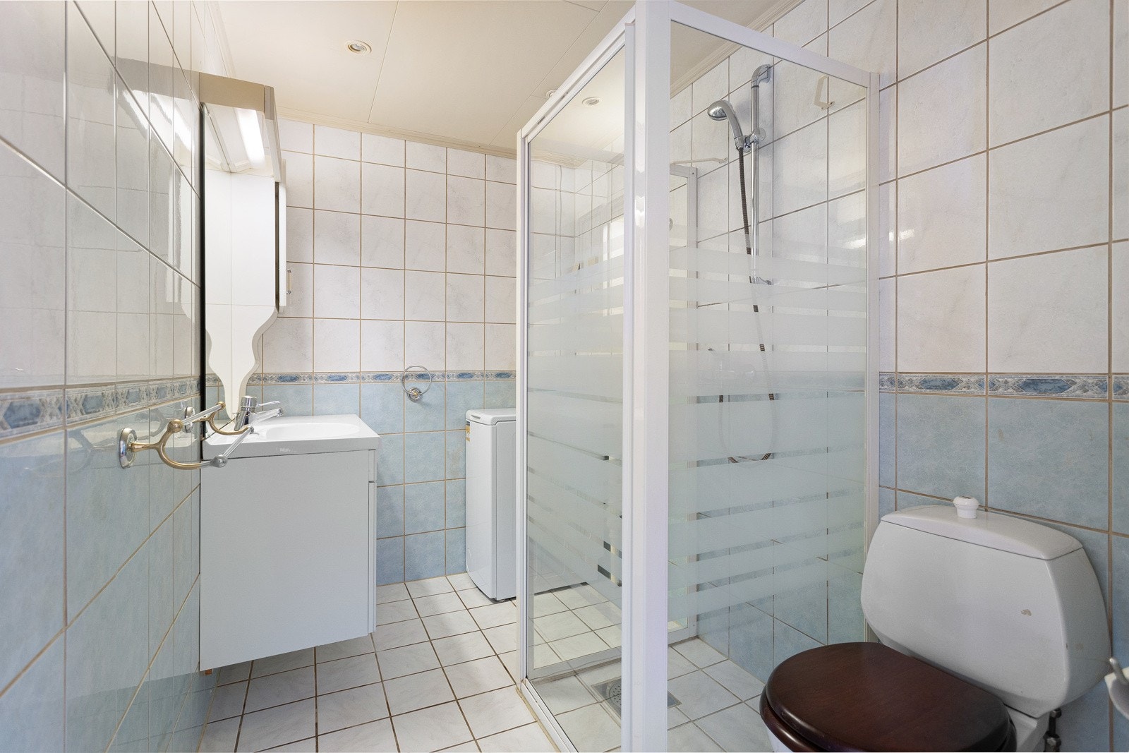 Romslig bad fra 90-tallet med opplegg for vaskemaskin. Galleribilde