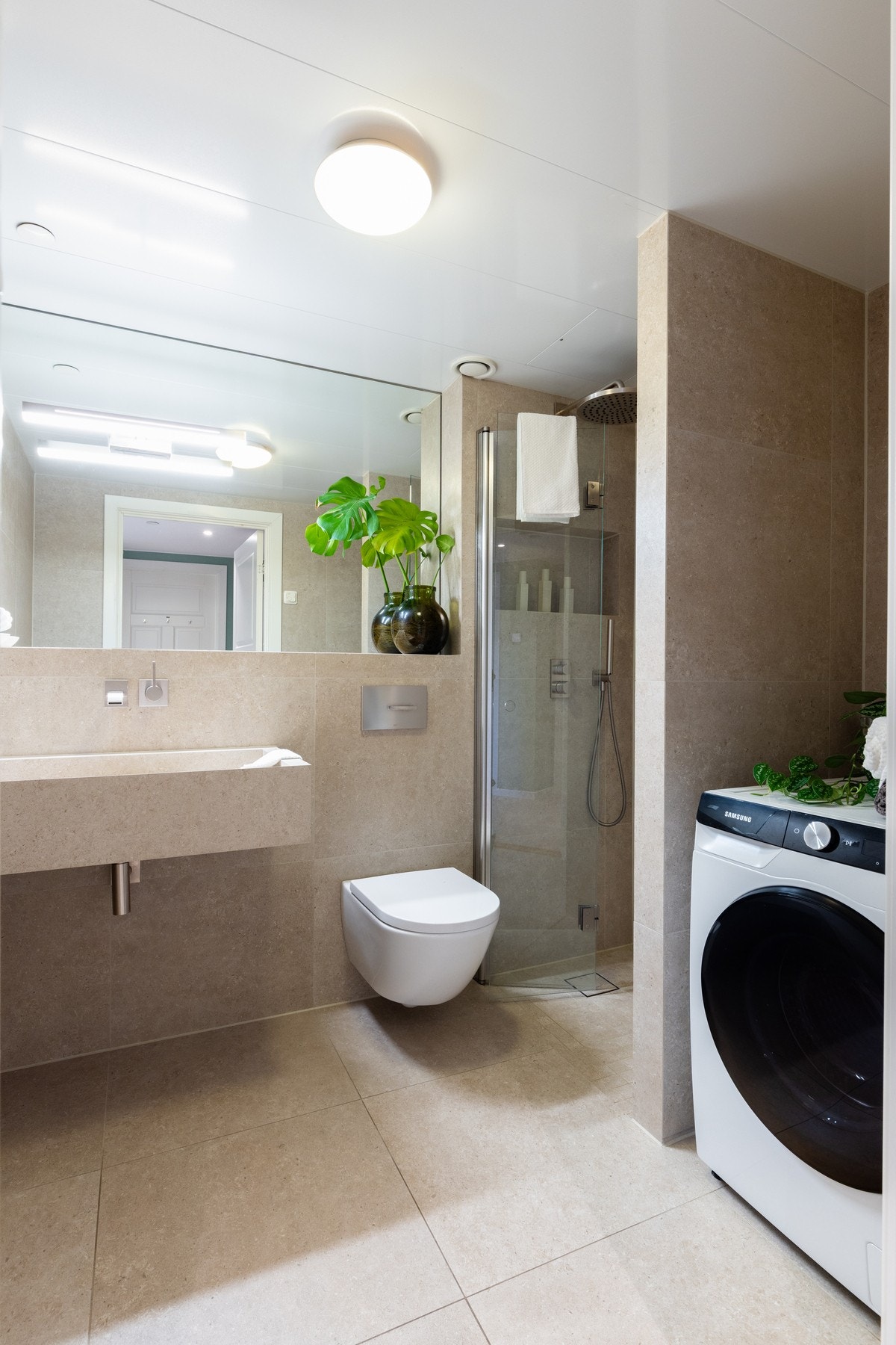 Det flotte, flislagte baderommet ligger i tilknytning til entréen og ble i 2022 oppgradert med flis på flis. Videre er det regnfallsdusj i dusjnisje og det er opplegg for vaskemaskin. Galleribilde