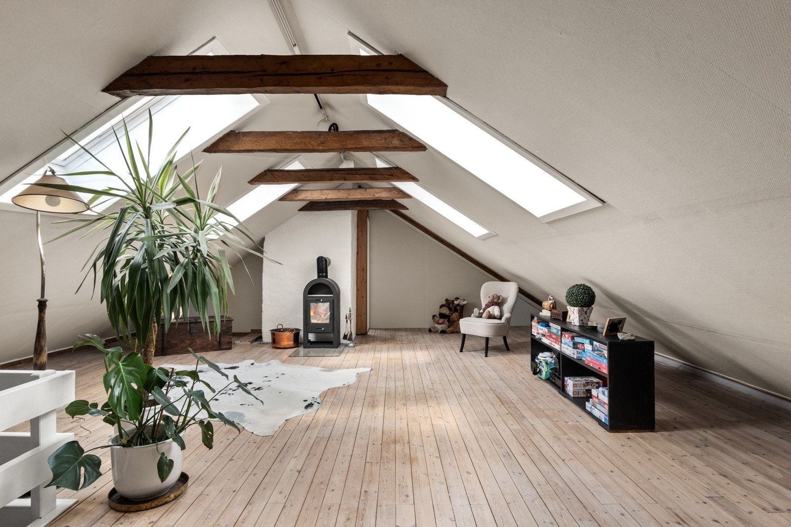 oftsstue med skråtak, synlige trebjelker og hvite vegger. Rommet er lyst og koselig, med en rustikk og naturlig atmosfære. Galleribilde