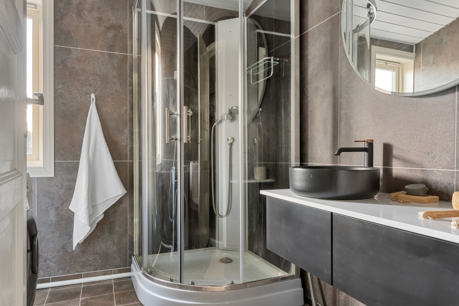 Badet er innredet med toalett, helstøpt servant, skuffer under servant med slette fronter, usjkabinett, opplegg for vaskemaskin. Galleribilde