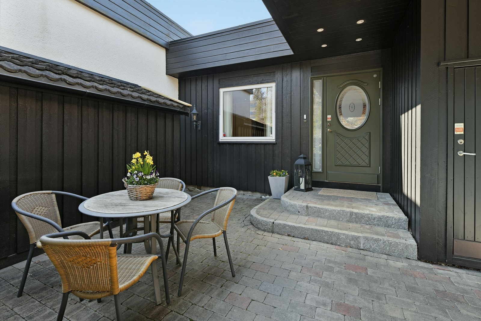 Delvis overbygget inngangsparti med downlights i himling - plass til sittegruppe med morgensol Galleribilde