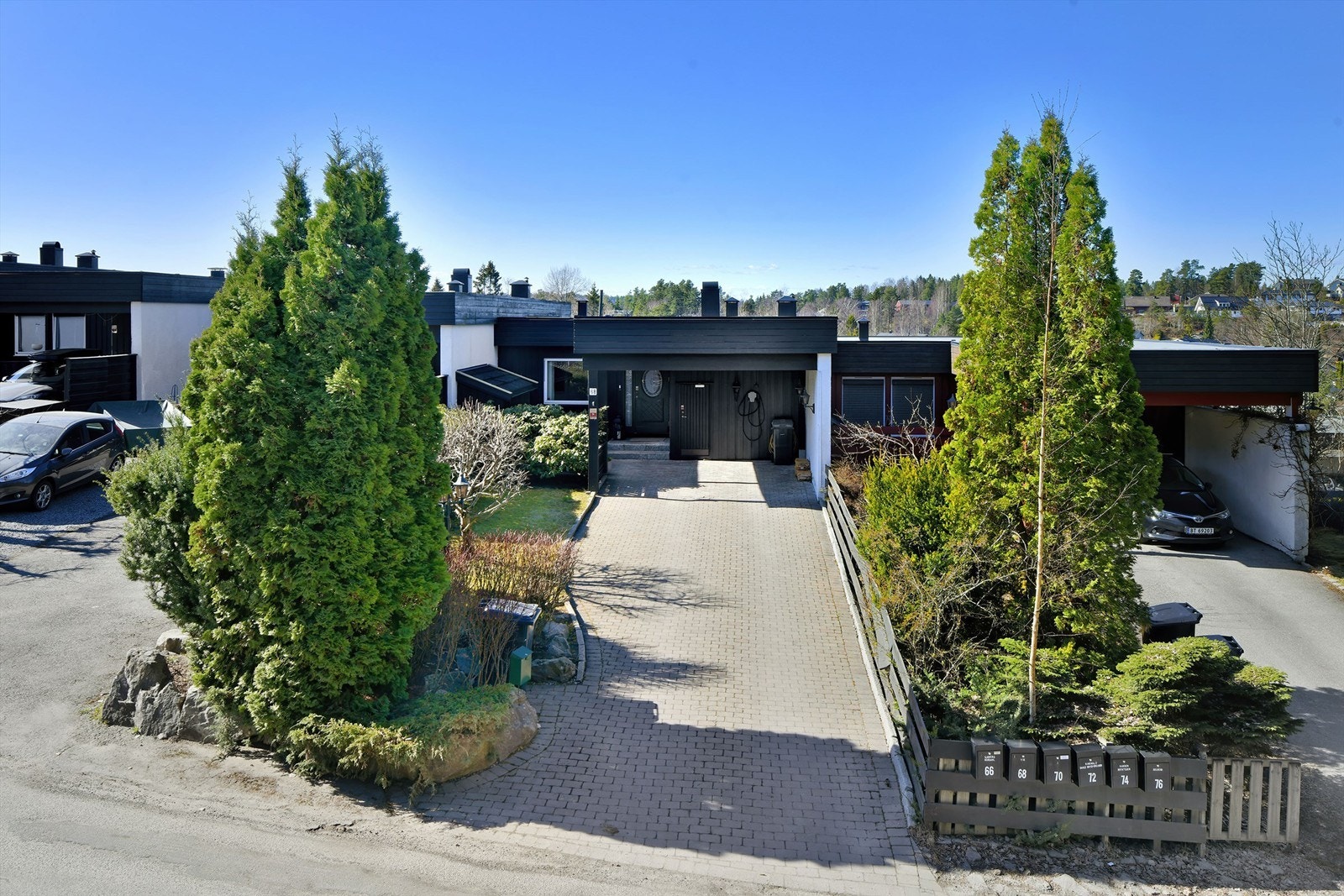 Carport med plass til én bil (med elbil-lader) - belegningsstein på gårdsplass med god plass til parkering Galleribilde