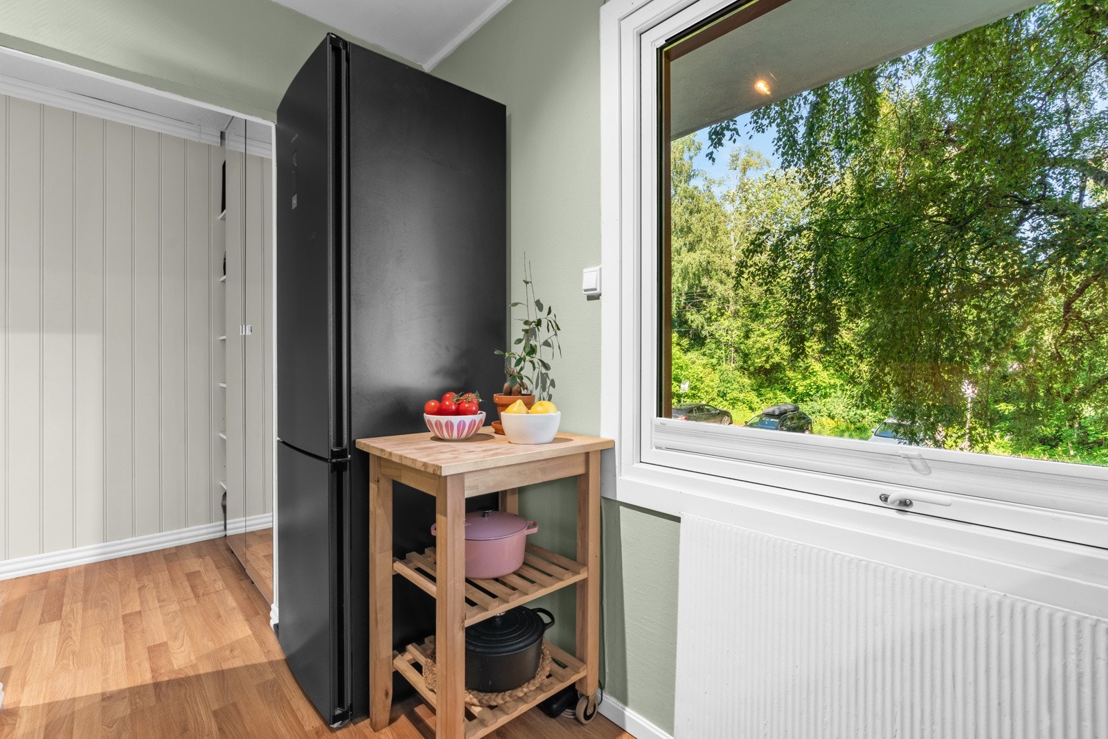 Det er hvite fliser over benken, opplegg for oppvaskemaskin og plass til kjøleskap. Galleribilde