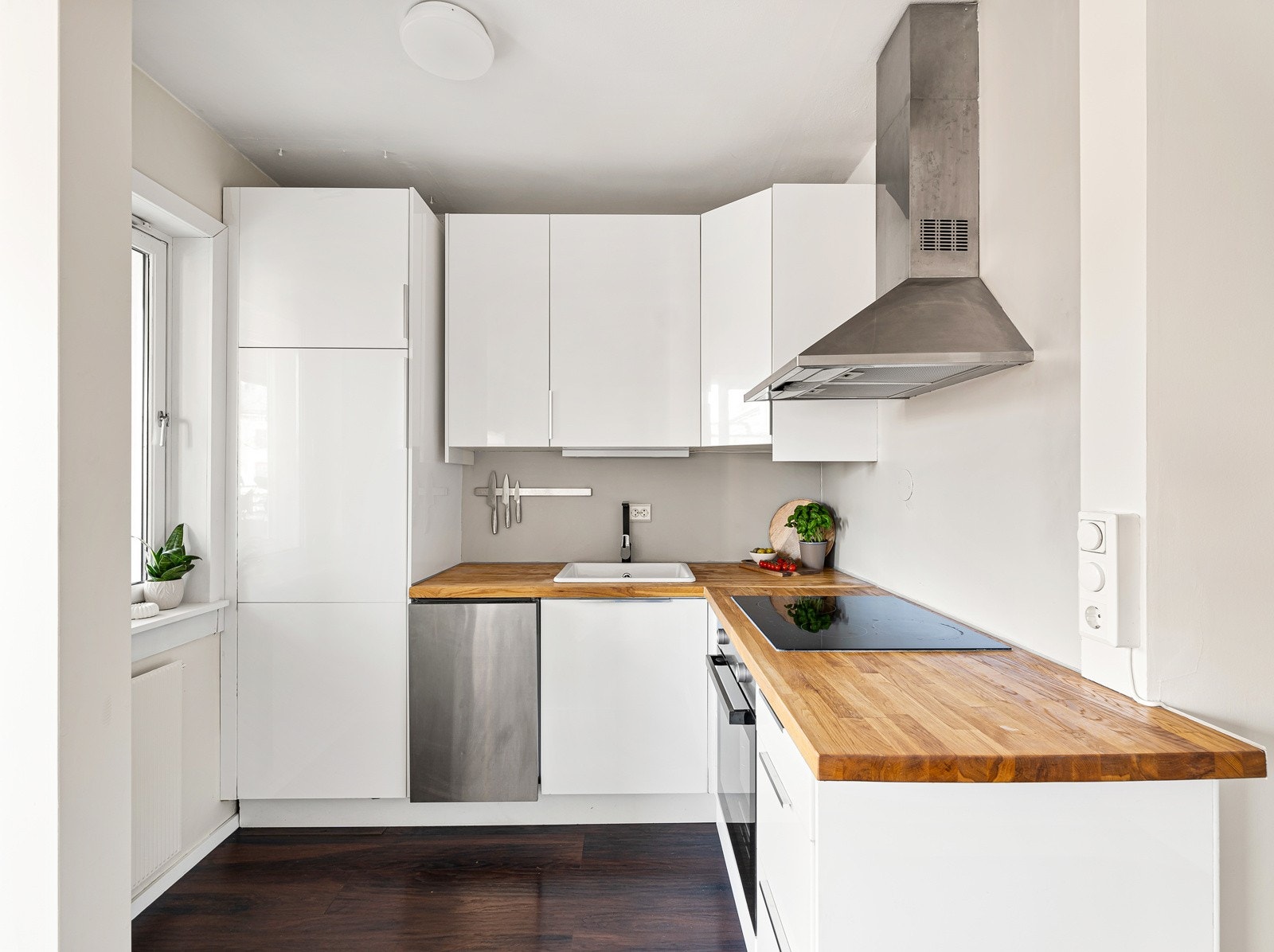 Moderne kjøkken med glatt laminert kjøkkeninnredning og benkeplate i tre. Praktisk utforming med god skapplass Galleribilde