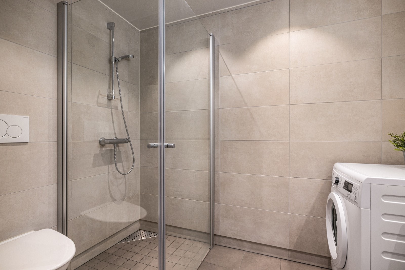 Badet er helfliset i delikate beige fliser. Det er gulvvarme og downlights i himling Galleribilde