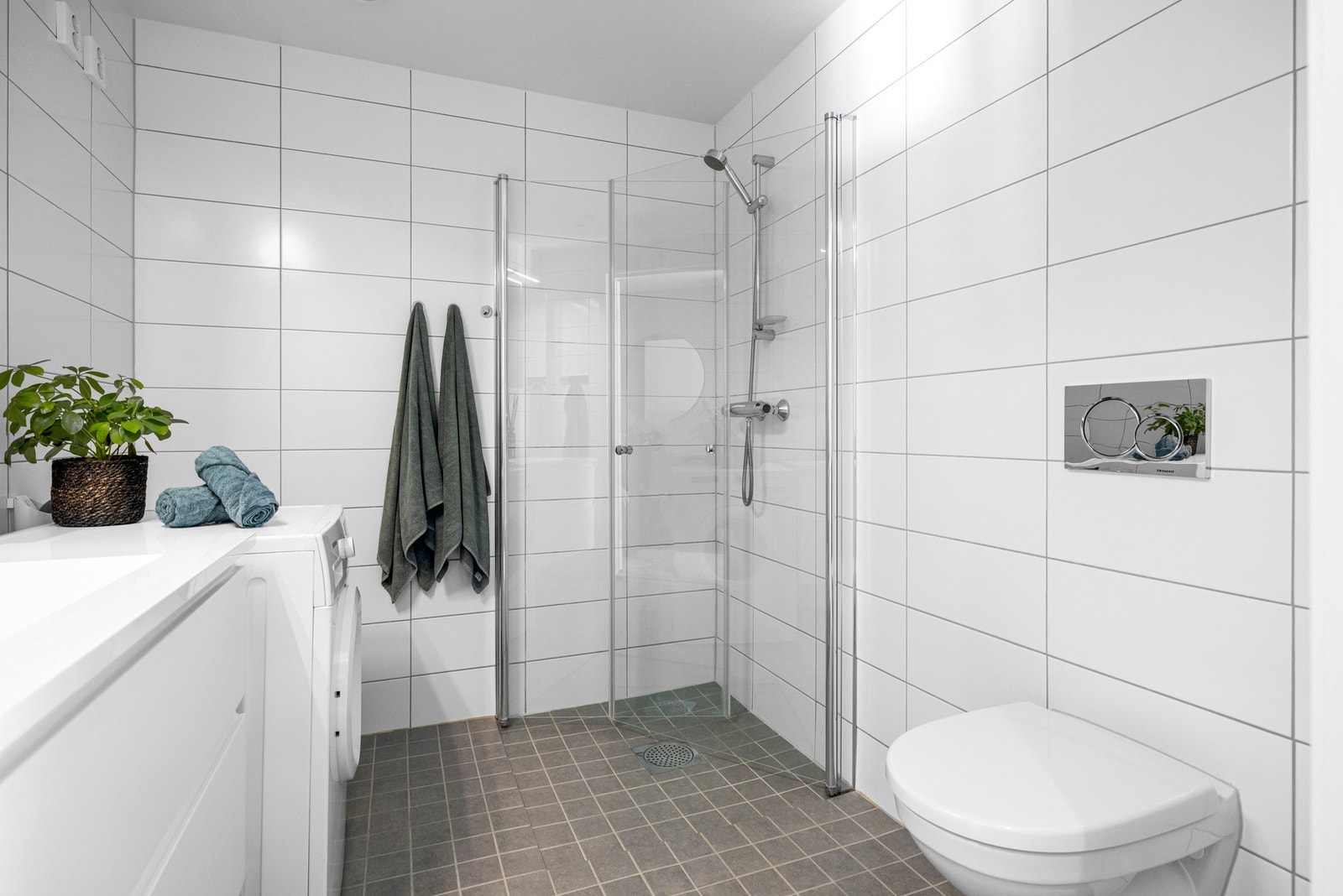 Boligen har et pent og tidløst innredet baderom av romslig størrelse. Her har du flisvalg av hvite, avlange veggfliser og grå, rutede gulvfliser. Galleribilde