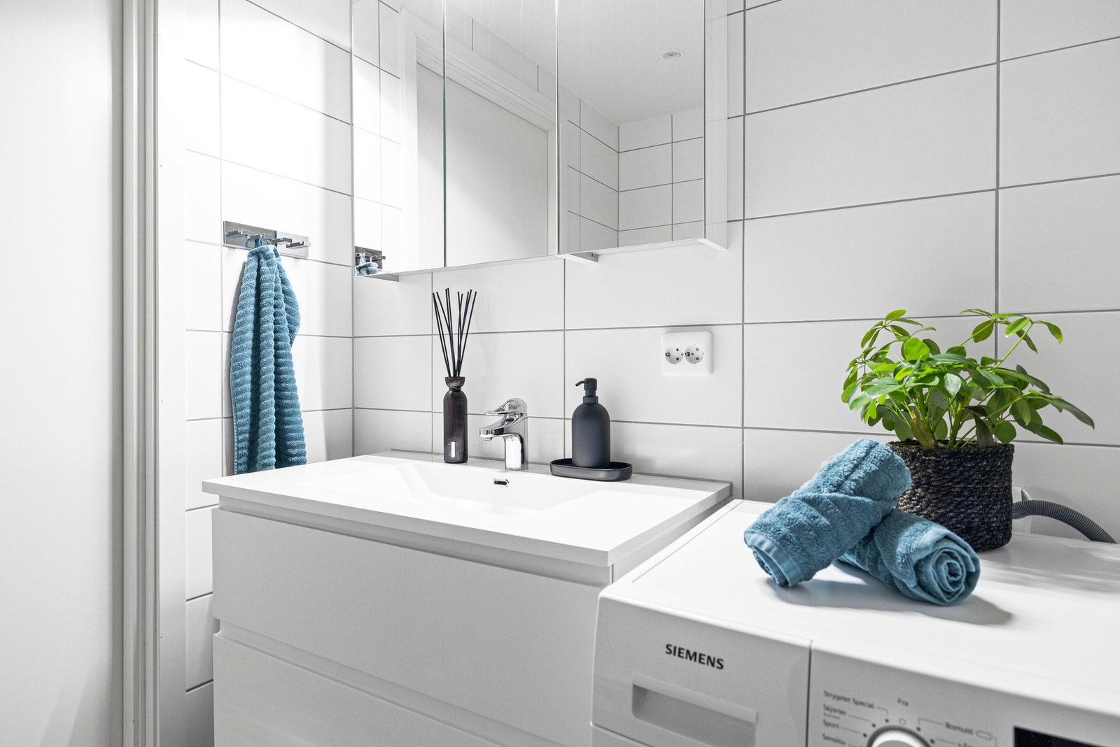 Hvitt servantskap med heldekkende servant, samt speilskap med lysarmatur på vegg. Galleribilde