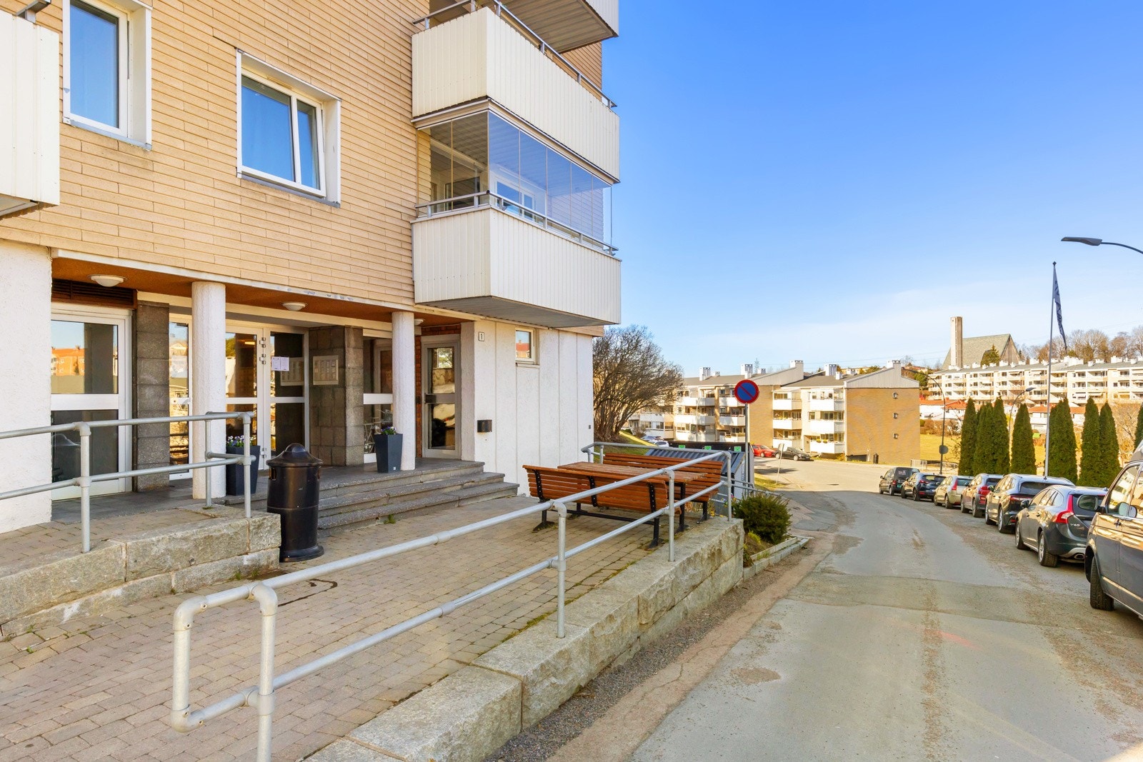 Inngangsparti - Bygget har heis til etasjene og ligger omkranset av store fellesarealer med plen, frodige treklynger, prydvekster, steinsatt adkomst og asfaltert parkeringsplass. Fra leiligheten er det ca. 1,3 km til Manglerud barne- og ungdomsskole. Galleribilde