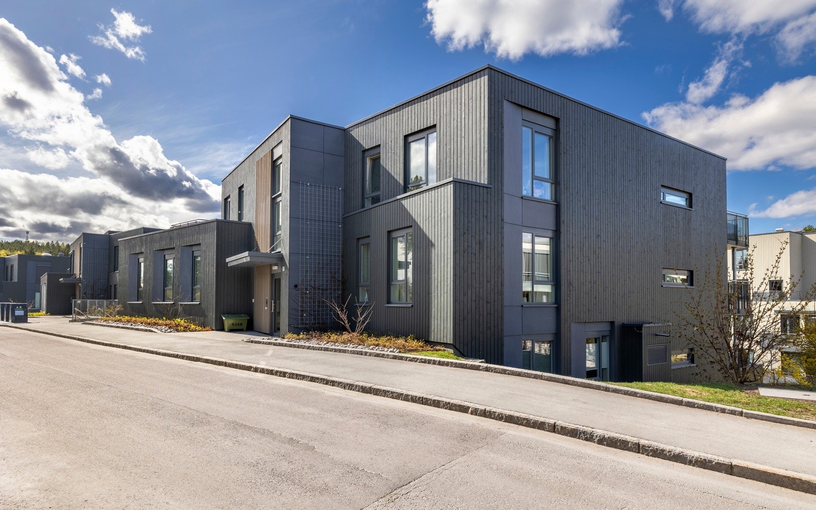 Sameiets tomt har et delvis skrånende terreng lekeplass og diverse beplantninger. Galleribilde
