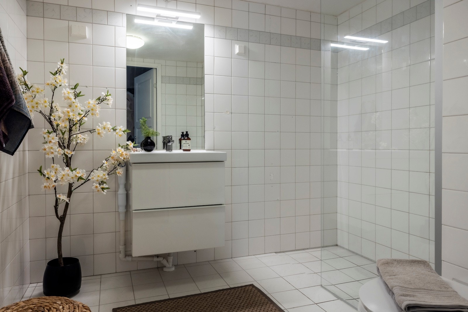 Flislagt bad med gulvvarme, opplegg for vaskemaskin, servant med innredning, dusjhjørne med glassvegg og toalett Galleribilde