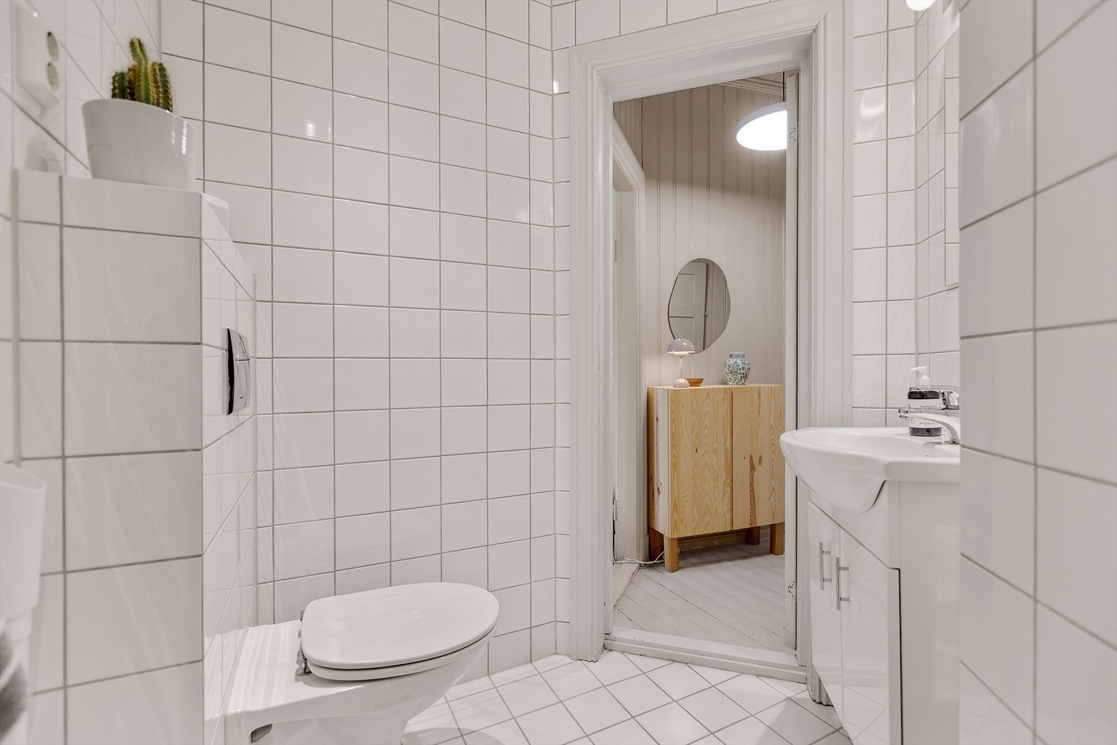 Baderomsinnredningen består av heldekkende servant nedfelt i underskap, speil m/lys, veggmontert toalett, dusjhjørne og opplegg for vaskemaskin. Galleribilde