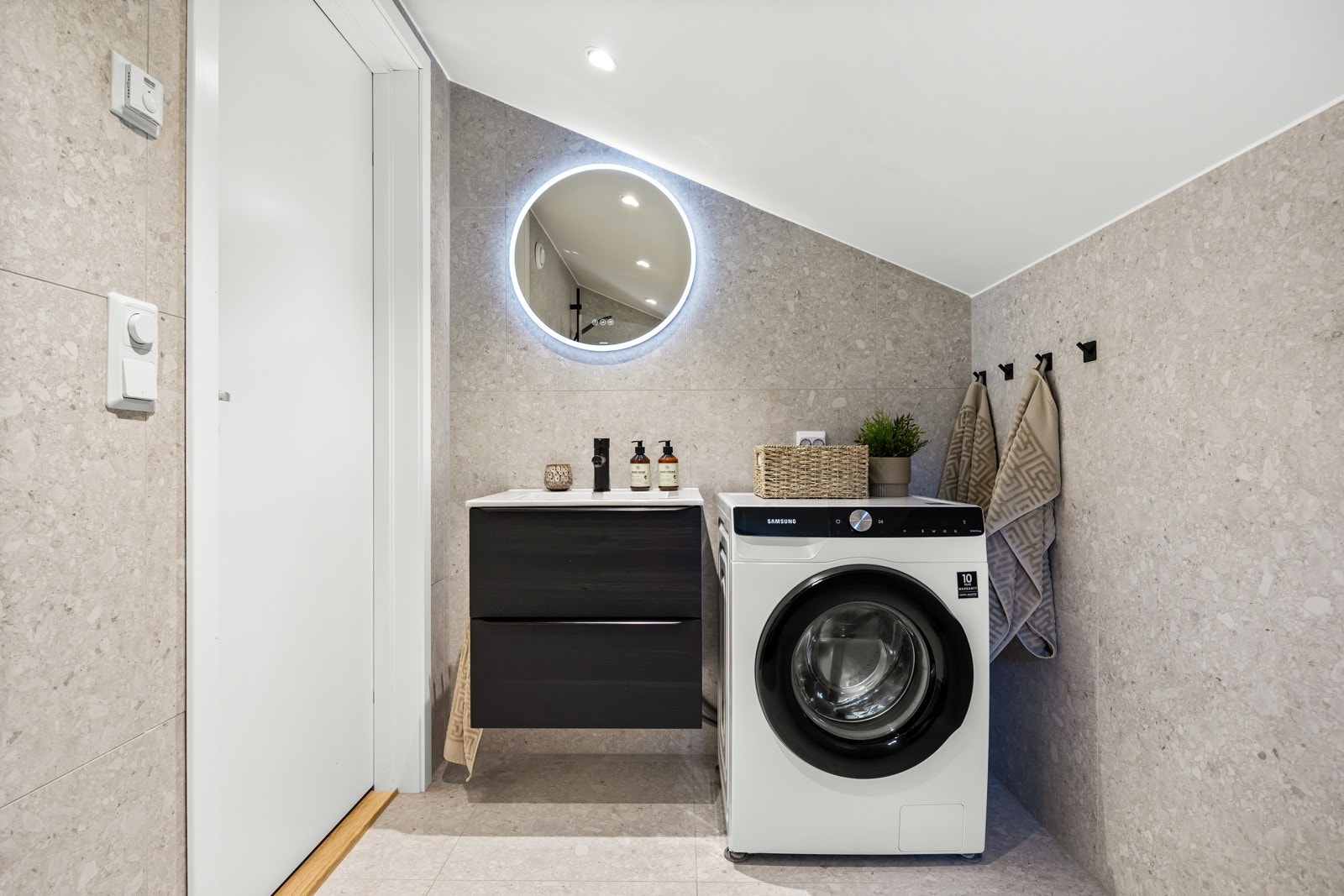 Badet er innredet med en mørk baderomsinndredning og vaskemaskin. Galleribilde