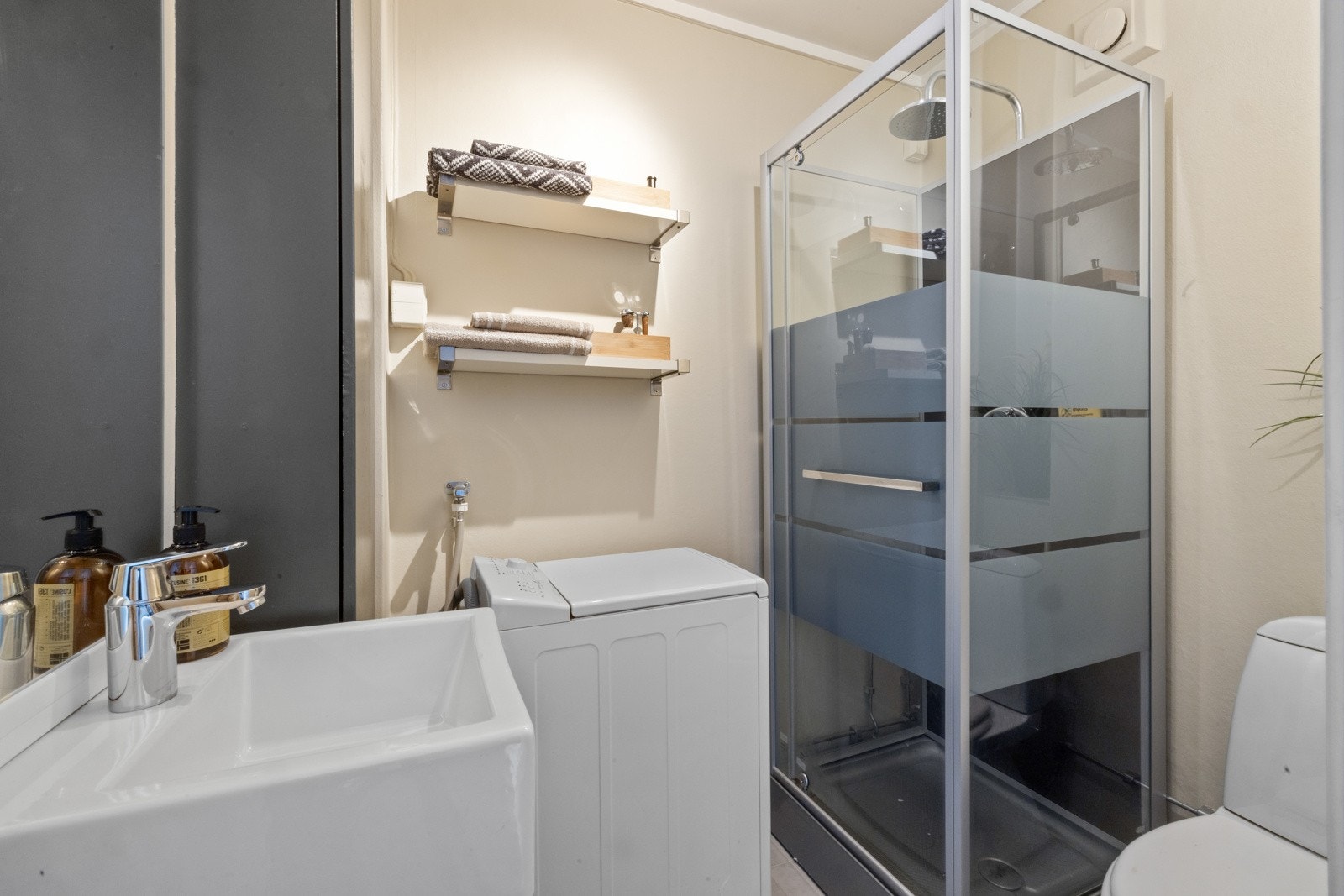 Badet er utstyrt med et servantskap med glatte fronter og heldekkende servant, samt speilskap med belysning over. Videre har badet gulvmontert toalett og dusjkabinett med svingdør og dusjutstyr. Opplegg til vaskemaskin. Galleribilde