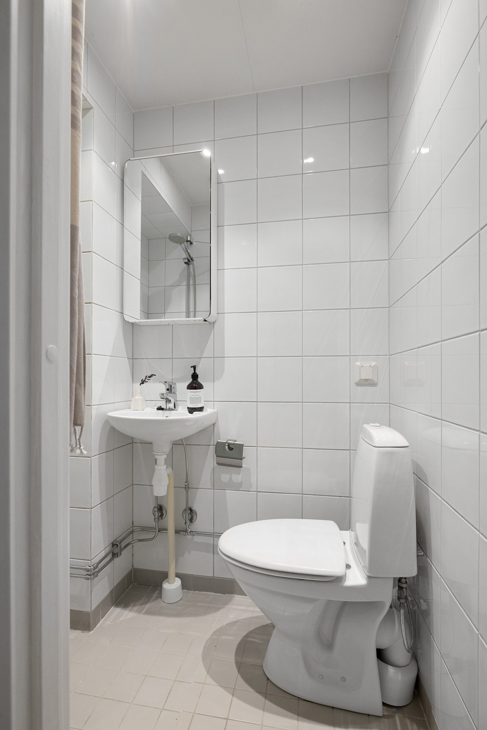 Flislagt baderom fra 2007 med veggskap med speilfronter, dusjnisje og gulvstående klosett. Galleribilde