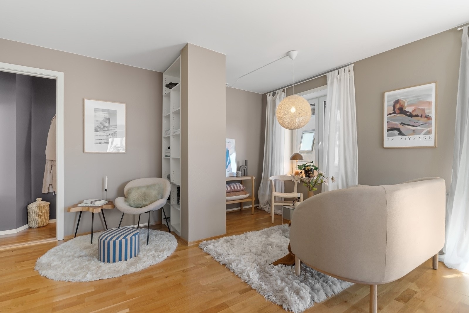 Stuen er oppdelt i flere soner, med plass til sofa og tv-møblement, sittekrok med bokhylle og spisebord inn mot den åpne kjøkkeninnredningen Galleribilde