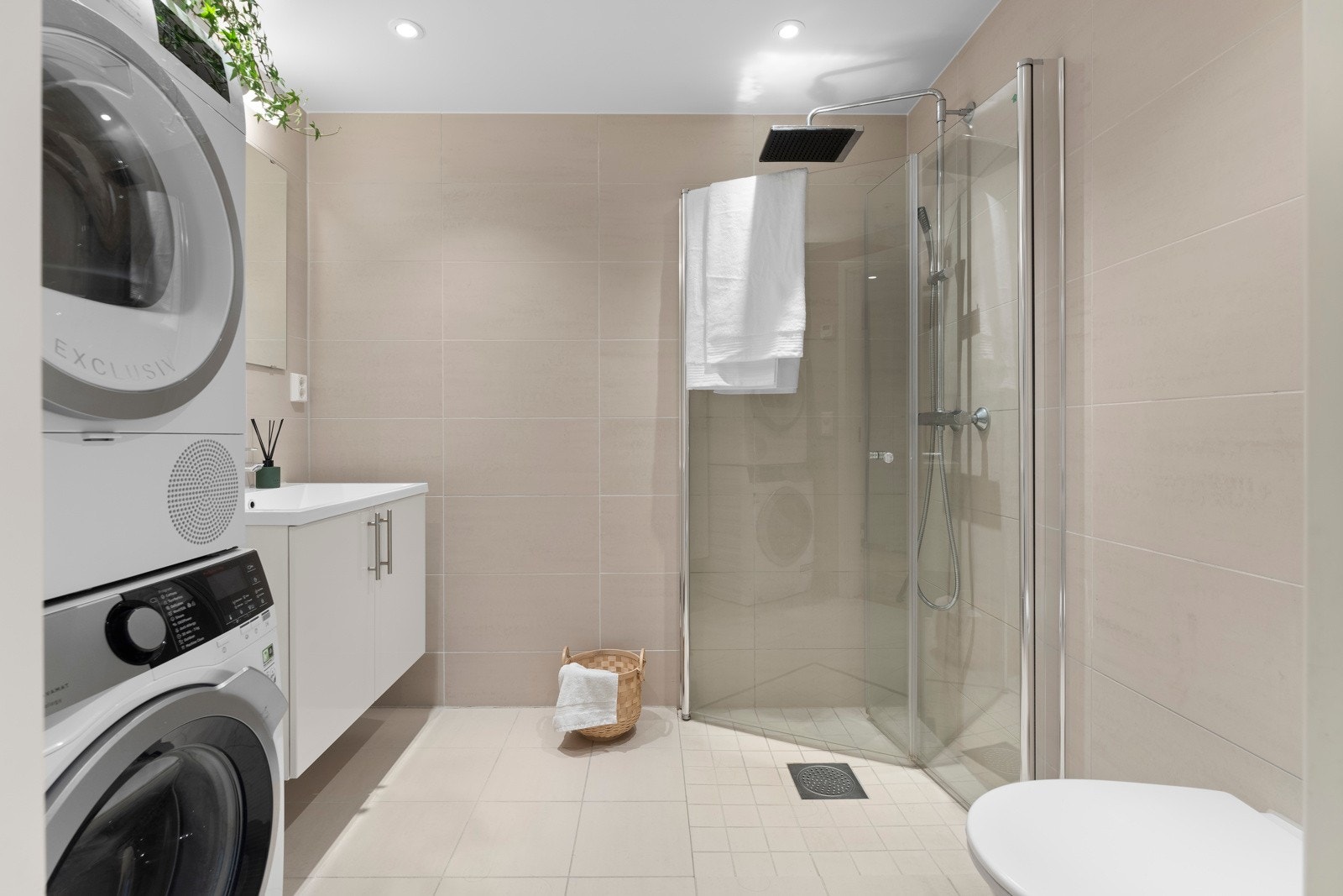 Badet har dusjhjørne med svingbare dører i glass, veggmontert toalett og servantinnredning med speil. Opplegg for vaskemaskin. Galleribilde