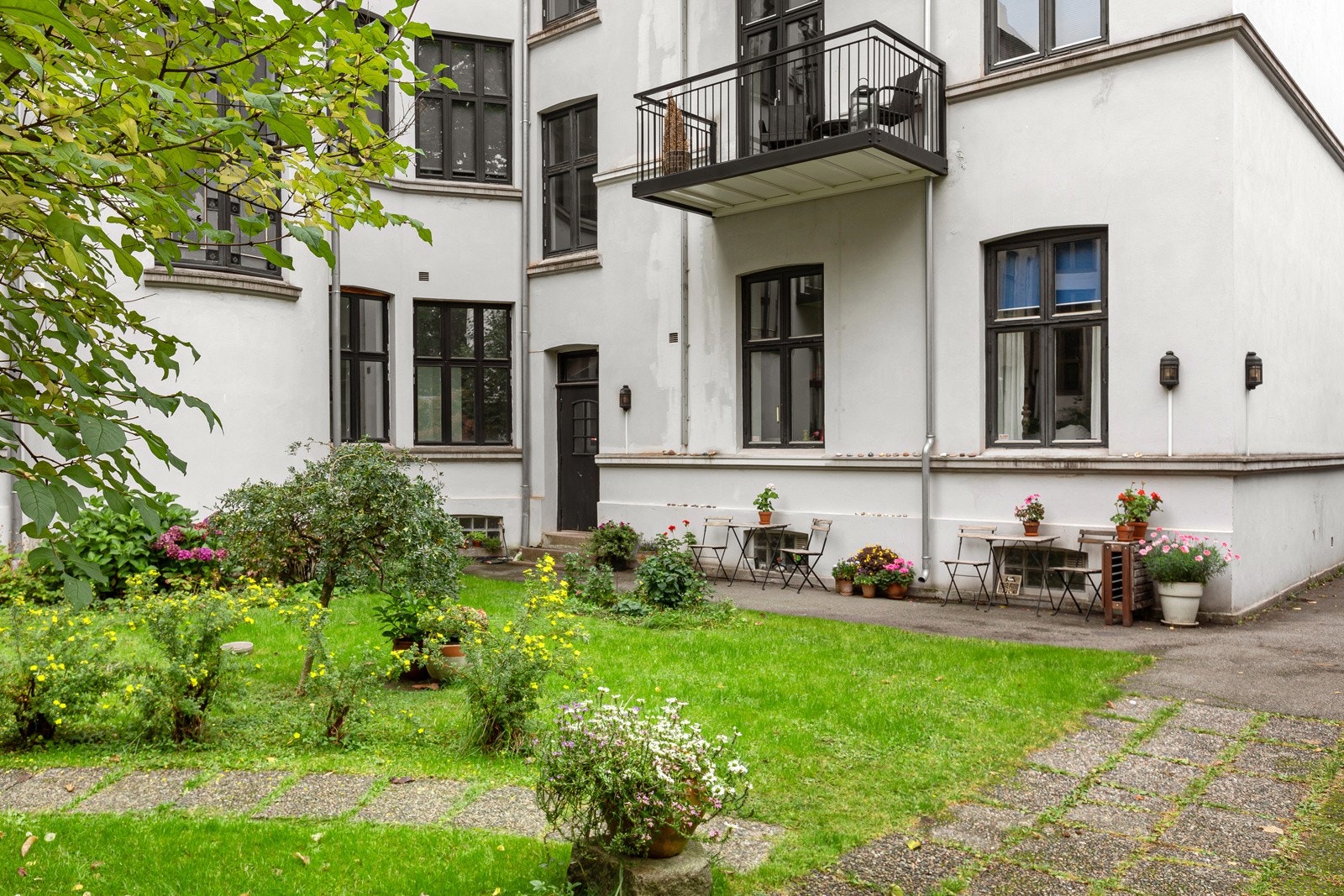 Fellesområdene i bakgård er opparbeidet med gressplen, beplantning, gjerde og betongheller Galleribilde