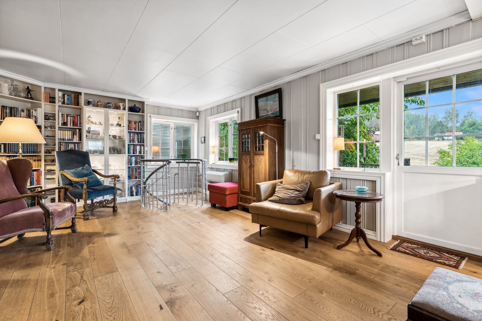 De generøse vindusflatene, sammen med verandadøren, slipper inn mye naturlig lys og skaper en luftig atmosfære i stuen. Galleribilde