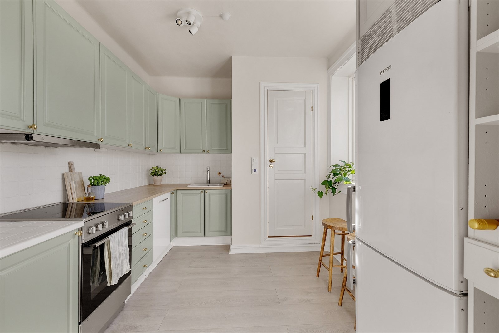 Kjøkkenet er i lyse profilerte fronter, laminat benkeplate, integrerte hvitevarer og en nedfelt kum. Galleribilde