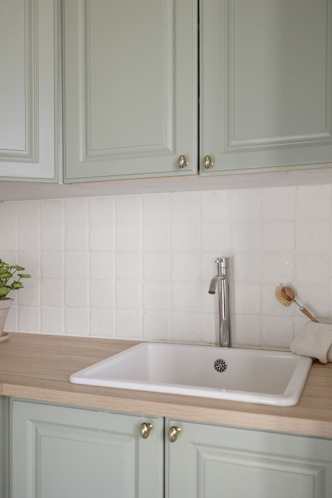 Det er lyse fliser på veggen under overskapene. Galleribilde