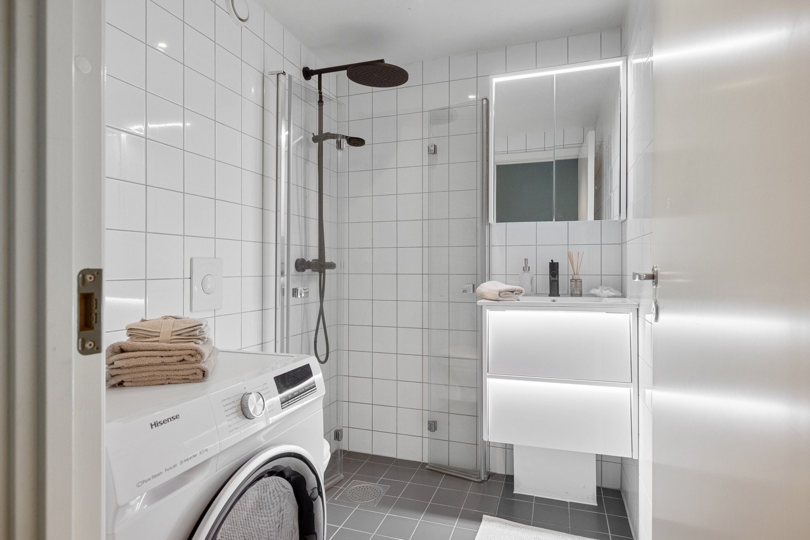 Badet er innredet med servant med underskuffer, speilskap med belysning, toalett og dusjhjørne med både håndholdt dusj og regnfallsdusj. Galleribilde