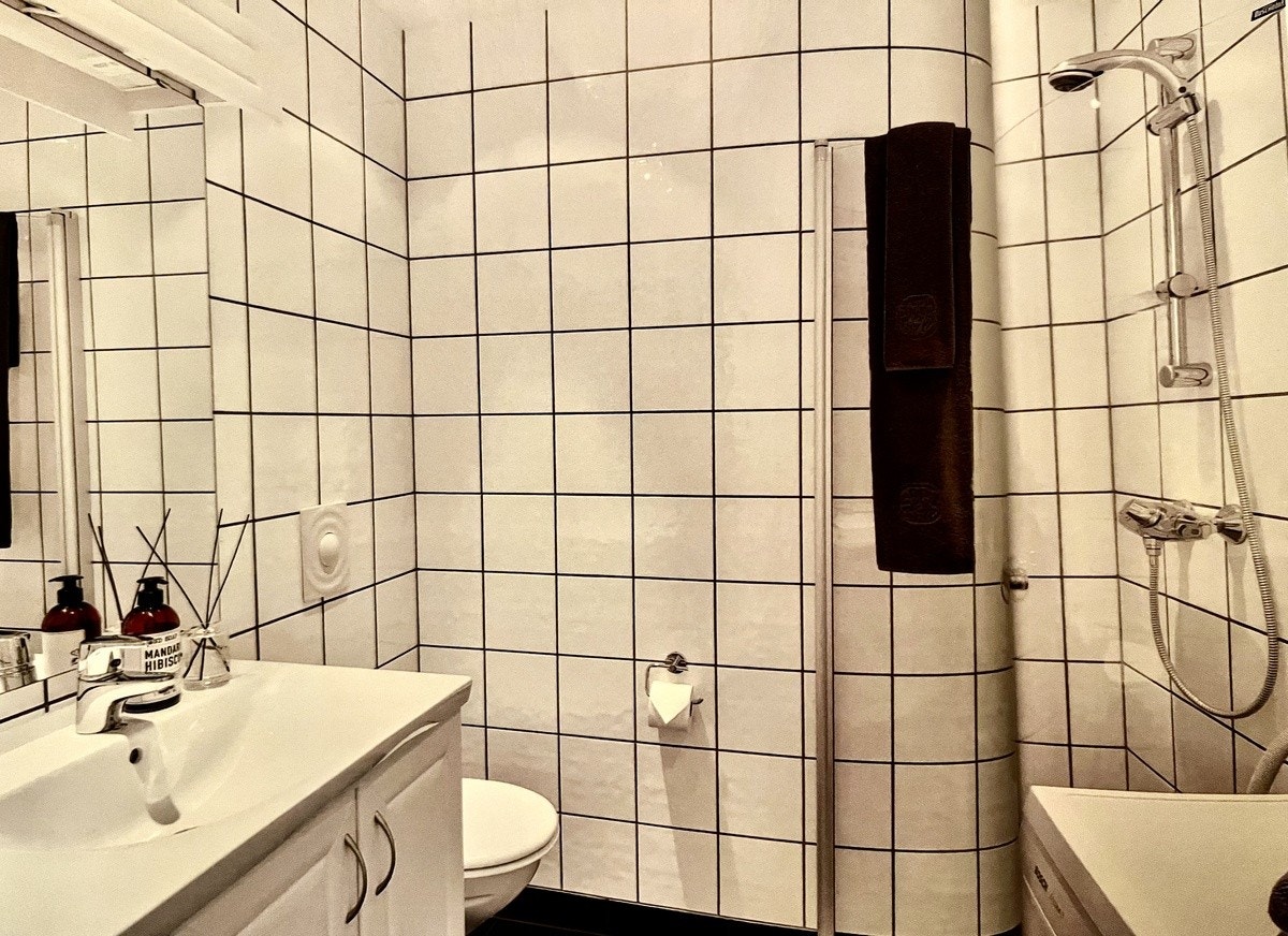 Moderne bad med vegghent WC, dusj og Miele vaskemaskin. Galleribilde