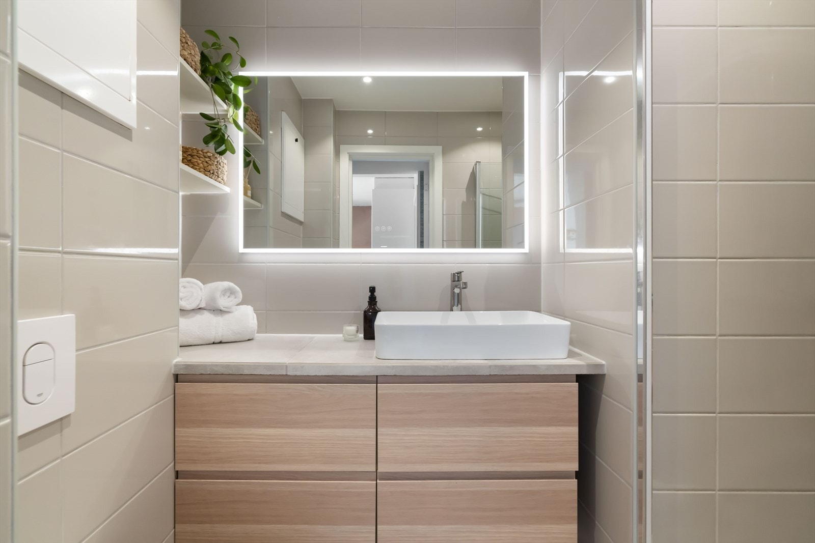 Innredet med et servantskap med god oppbevaring og en stilfull servantbolle på toppen, videre er det veggmontert klosett og en romslig regnfallsdusj med foldedører. Galleribilde