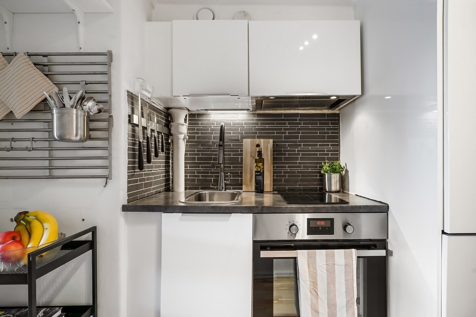 Fliser på vegg, belysning under overskap og laminat benkeplate. Integrert stekeovn, platetopp, kjøl/frys og oppvaskmaskin. Galleribilde