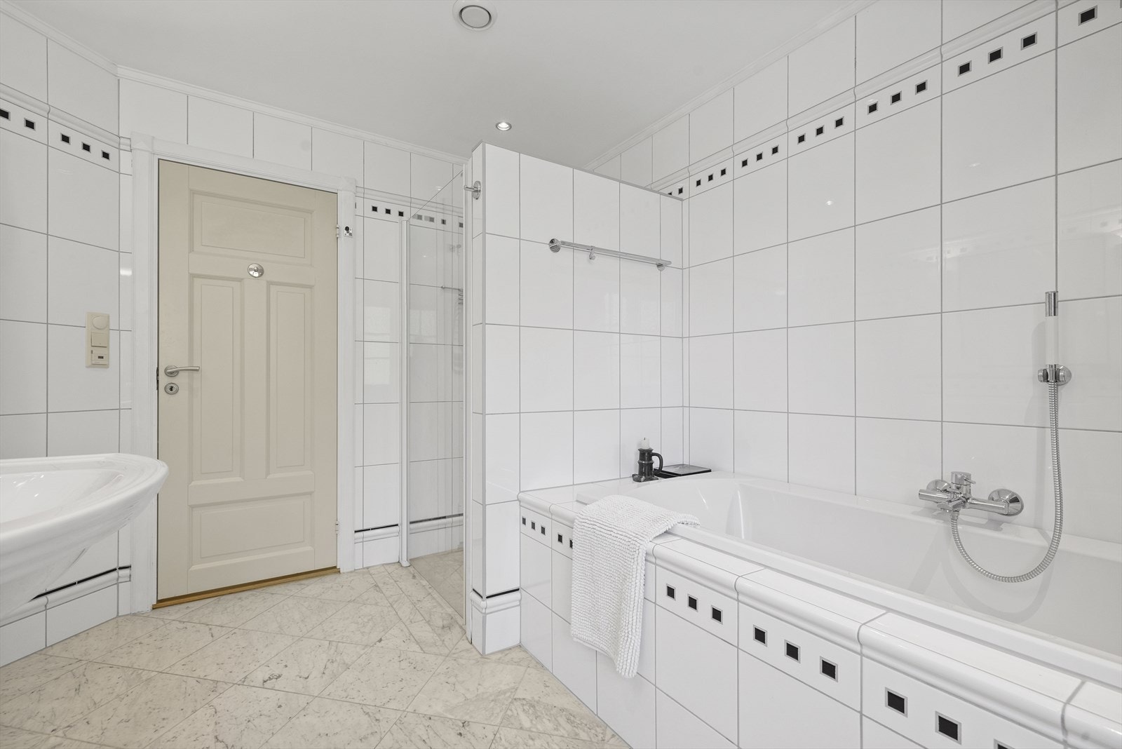 Badet inneholder en dusjnisje, innmurt badekar med flislagt front, søyleservant med blandebatteri, toalett. Påkostet Villeroy & Boch baderomsinnredning. Galleribilde
