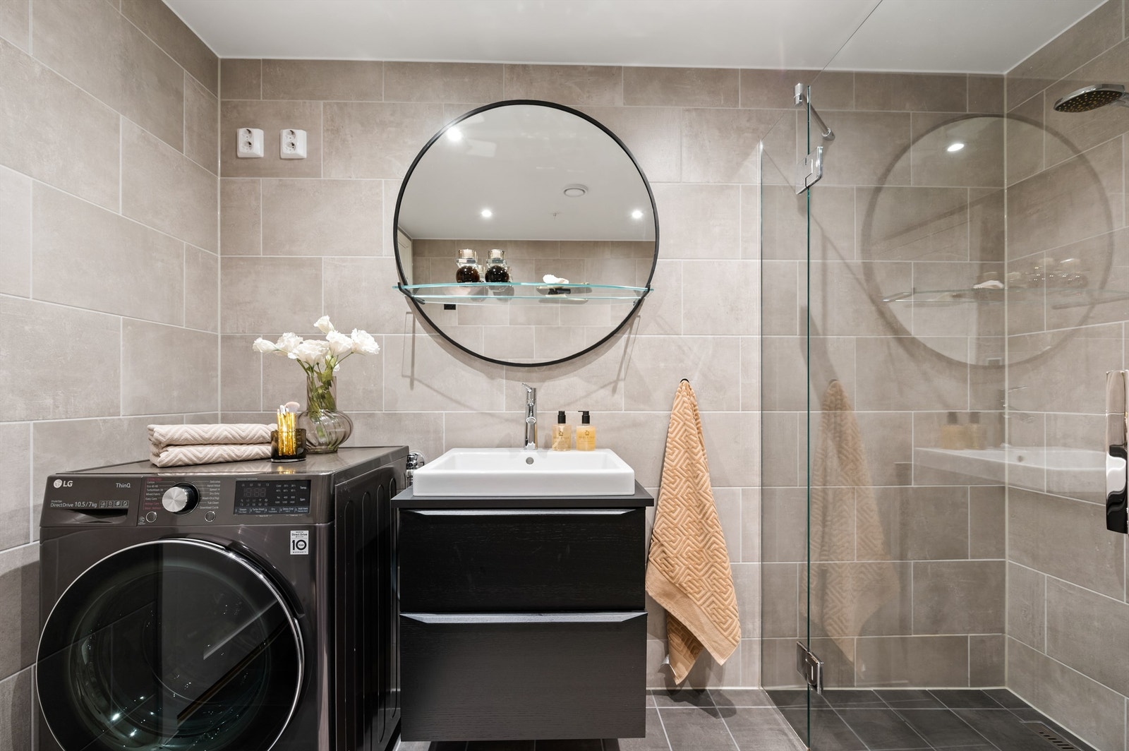 Innredet med vegghengt toalett og dusjhjørne med innfellbare glassdører. Videre har badet vegghengt servantinnredning med heldekkende servant og speil på vegg over servant. Opplegg for vaskemaskin, kombinert vaskemaskin/tørketrommel medfølger. Galleribilde