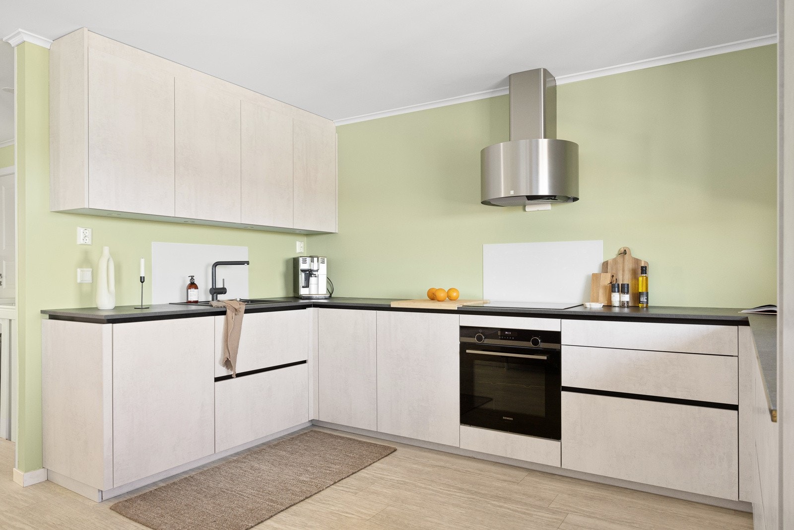 Kjøkken med glatte hvite fronter, laminat benkeplate med nedfelt komposittkum og ettgreps kjøkkenkran. Det er installert waterguard og komfyrvakt. Ventilator med avtrekk ut Galleribilde