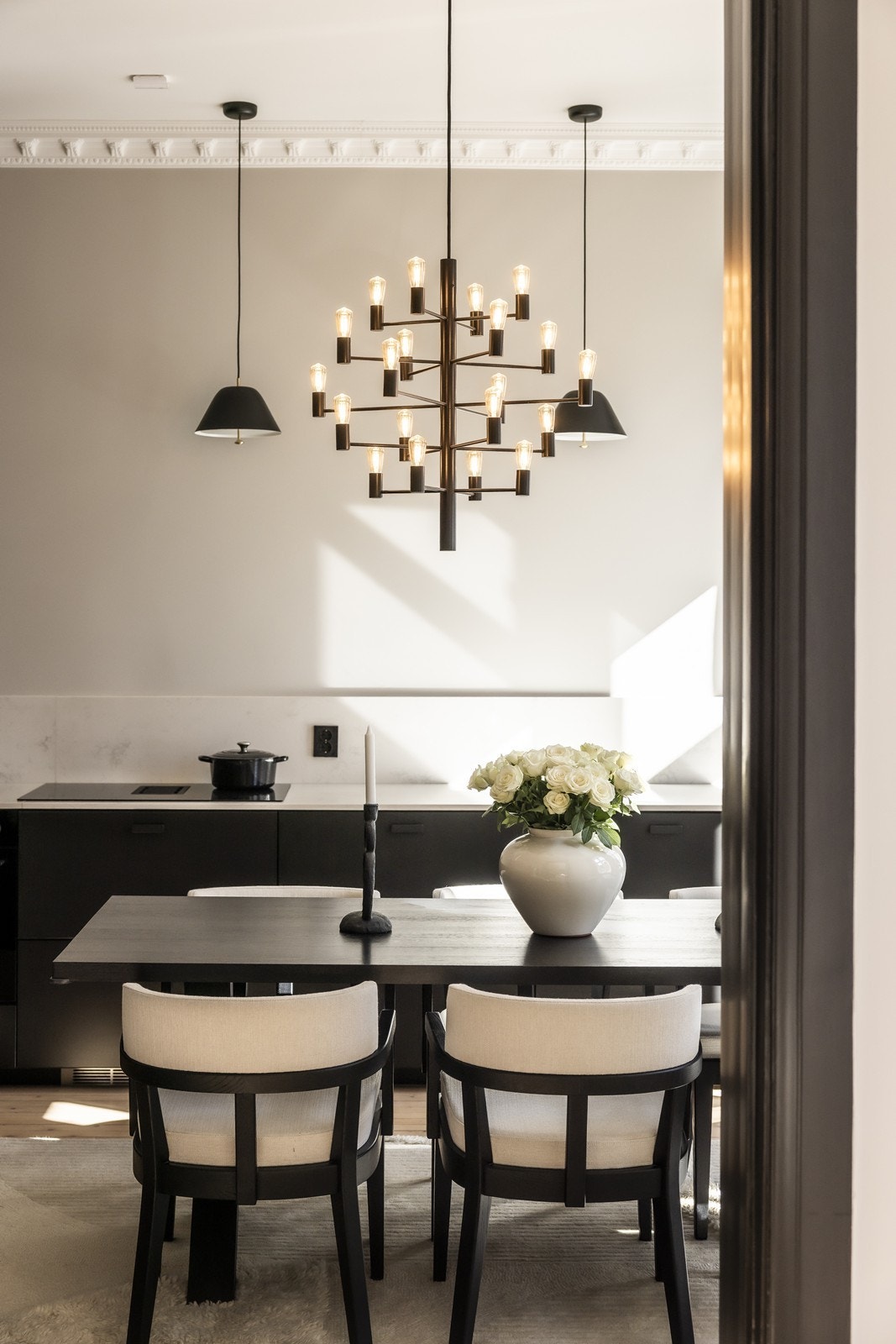 Sort kjøkkeninnredning med stilrene detaljer. Det er integrert kjøleskap, oppvaskmaskin, platetopp, stekovn, ventilator og vinskap. Galleribilde