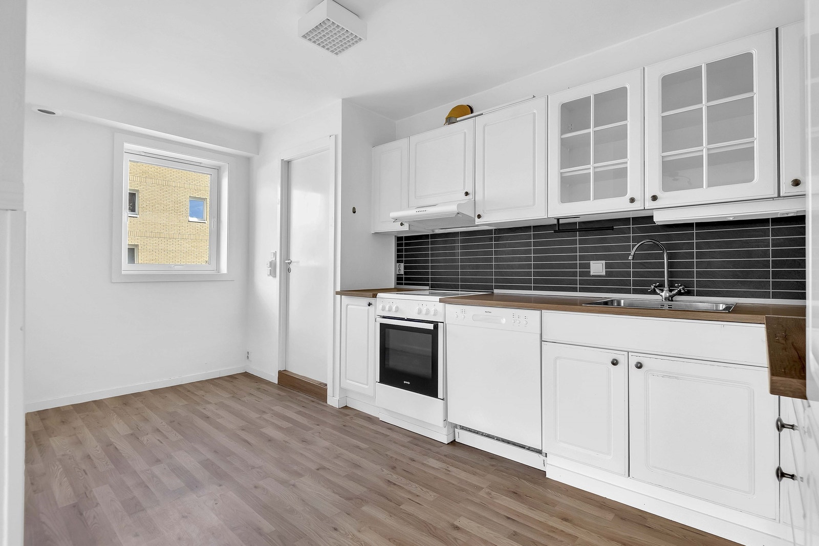 Kjøkken med lyse profilerte fronter \med laminat benkeplate med sponkjerne og oppvaskkum i stål med ett-greps blandebatteri. Galleribilde