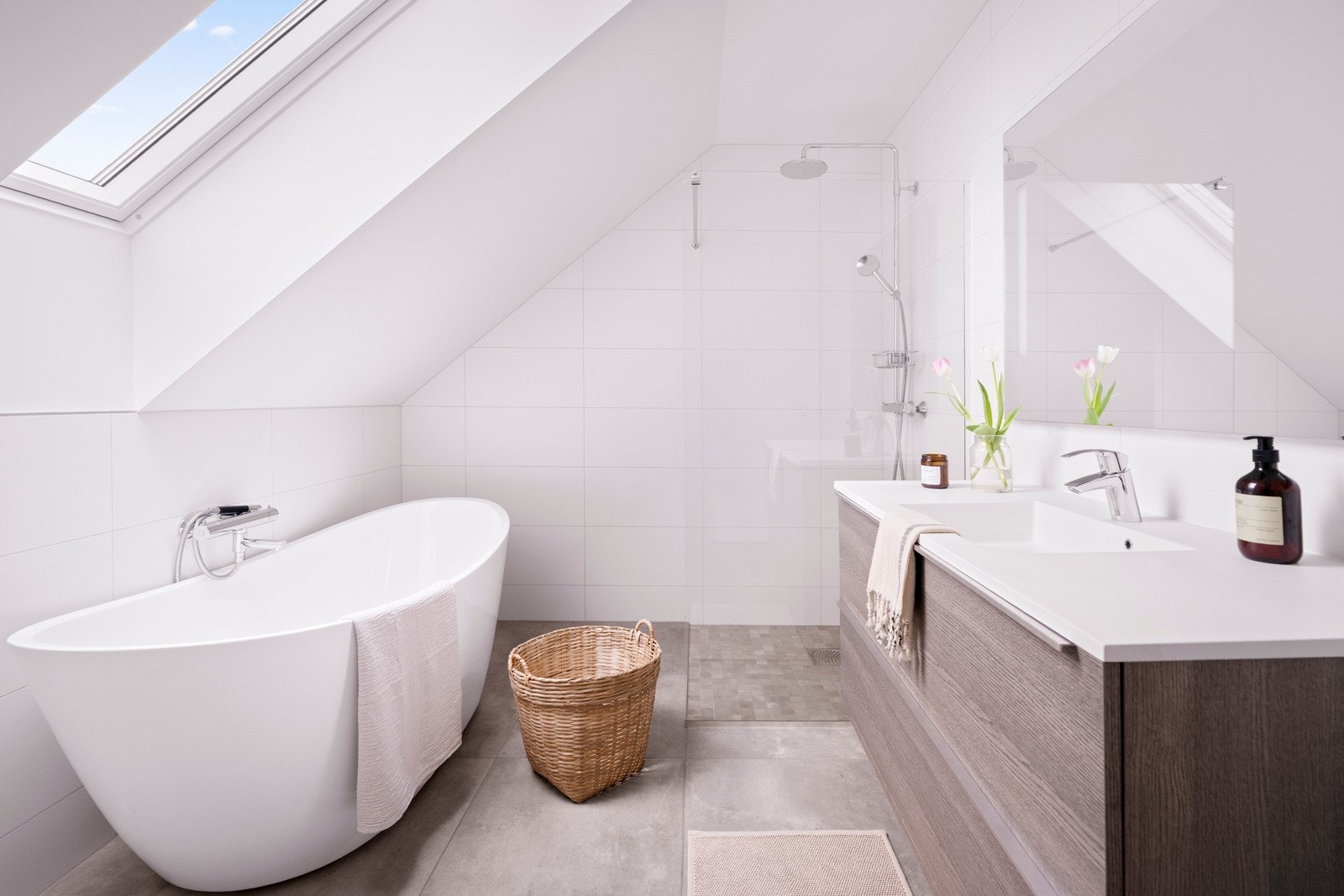 Ved soverommene og loftstuen i andre etasje er det et moderne og pent bad med lyse fliser på veggene og store, grå fliser på gulv med gulvvarme. Galleribilde