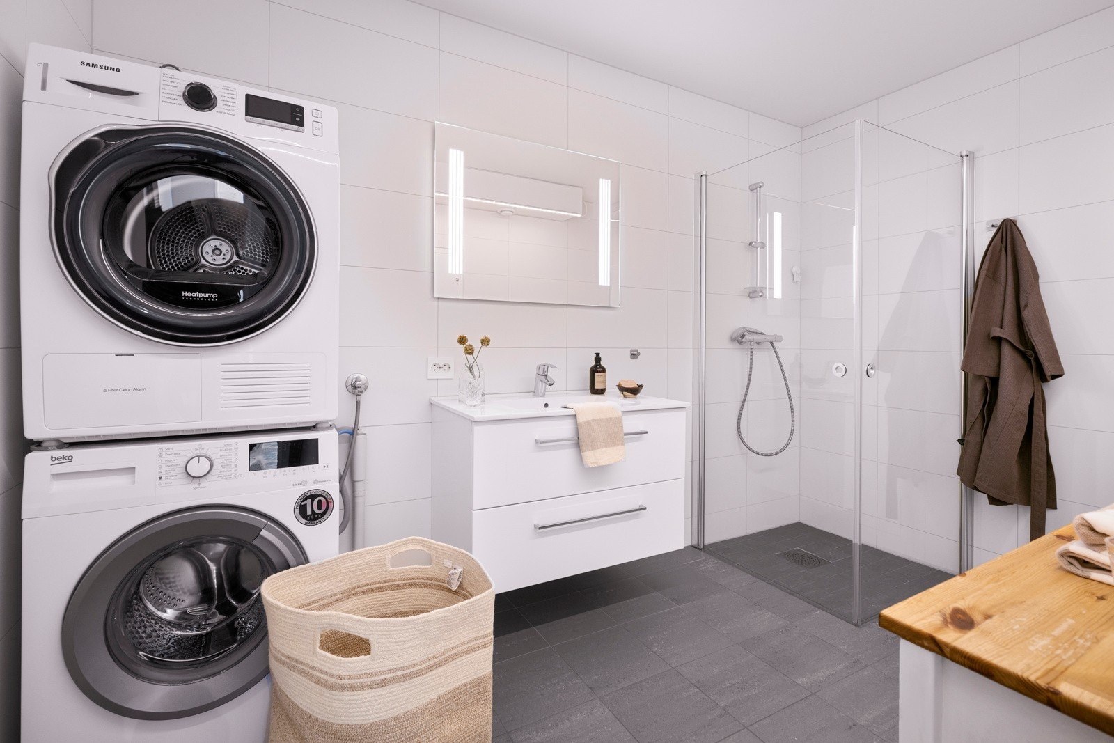 Leiligheten har et pent bad med hvite fliser på veggene og grå fliser på gulv med gulvvarme. Galleribilde