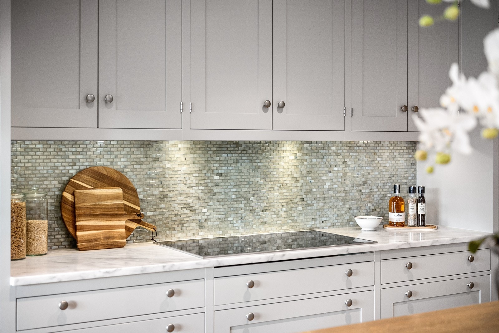 Delikat kjøkken med benkeplate i sten mot delikate fliser på vegg. Galleribilde