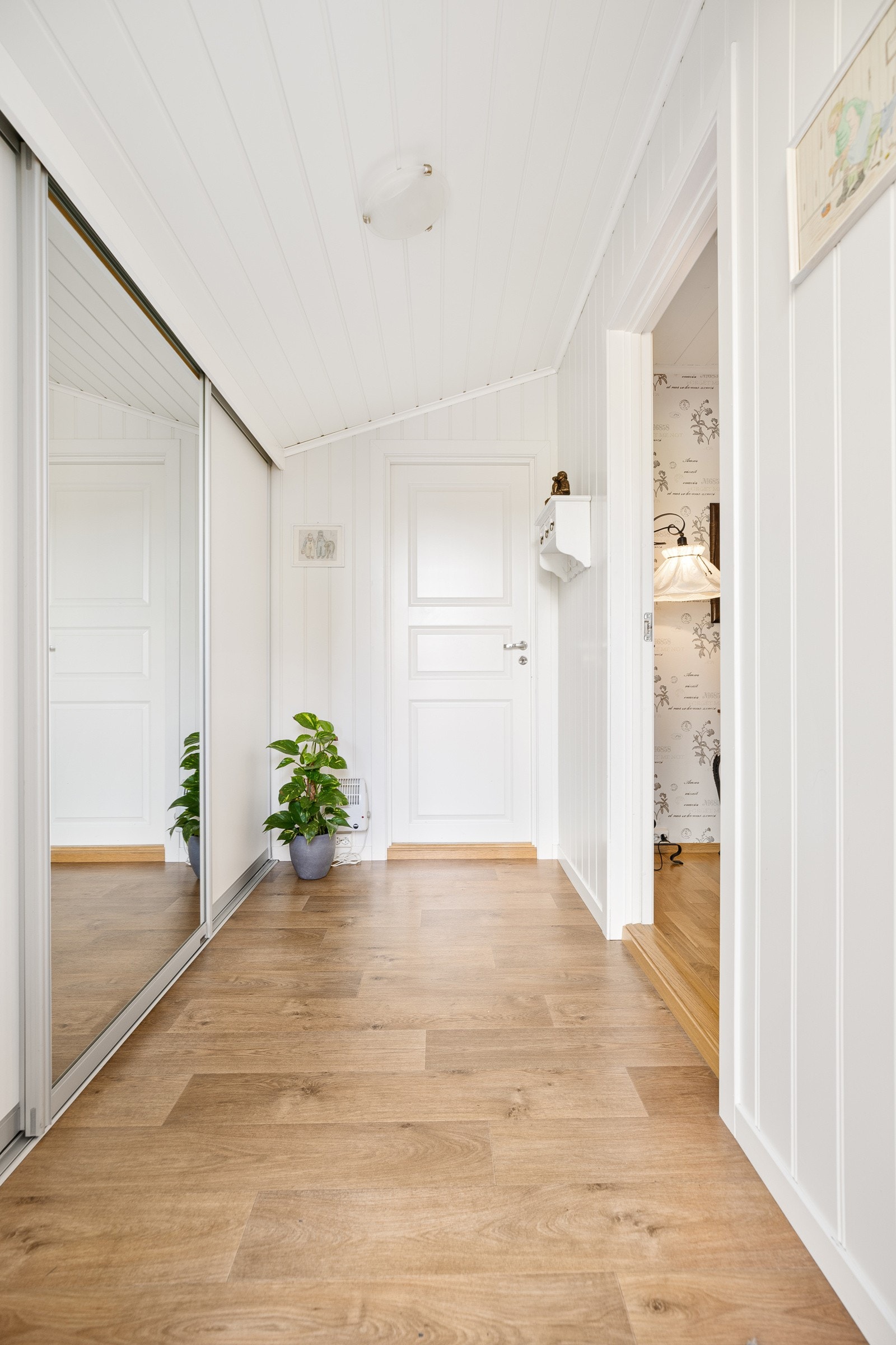 Man ønskes velkommen av et lyst vindfang, der jakkene enkelt ryddes bort i en skyvedørsgarderobe langs den ene veggen. Galleribilde