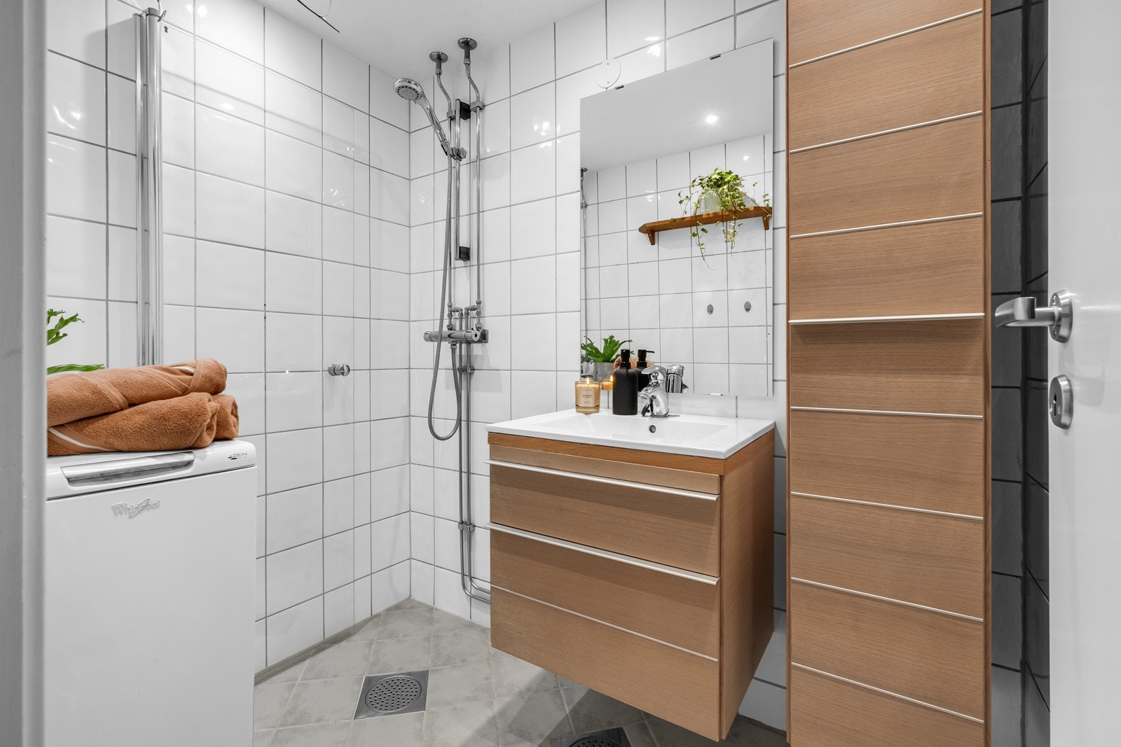 Baderommet fremstår som moderne og pent med opplegg for vaskemaskin og dusjhjørnet med svingdører i glass Galleribilde