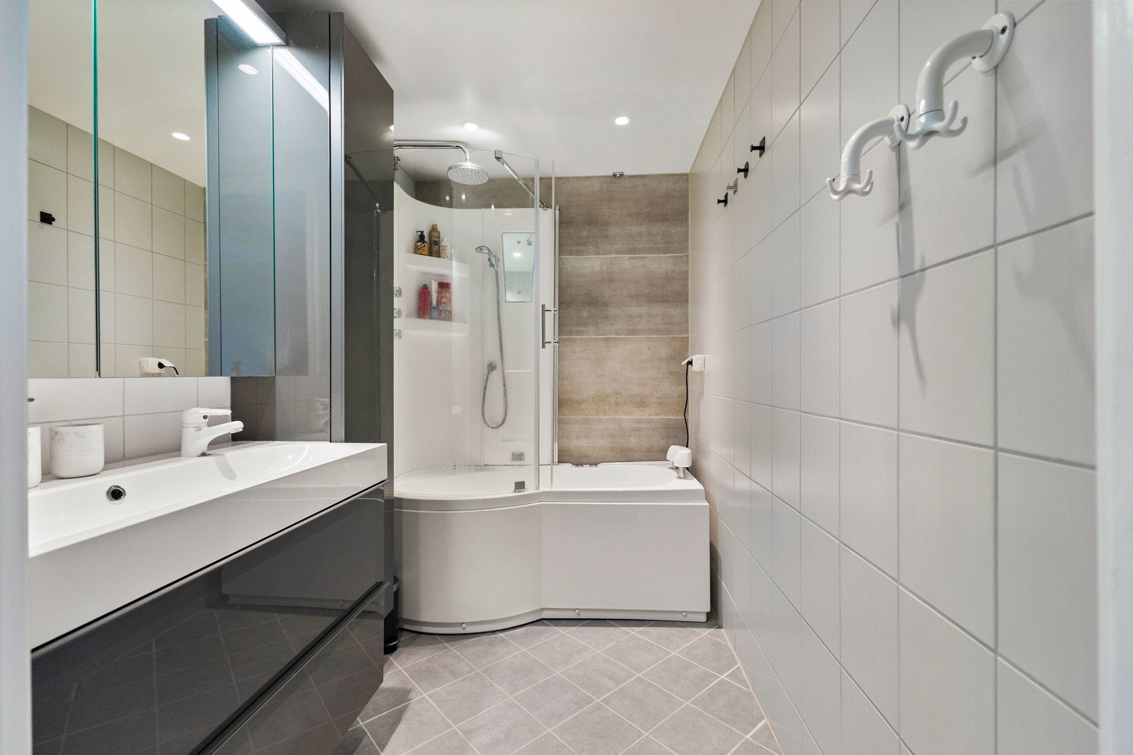 Lyst flislagt baderom med gulvvarme og downlight i taket. Badet ble pusset opp i 2017 i regi av borettslaget og fremstår moderne. Det er opplegg for vaskemaskin Galleribilde