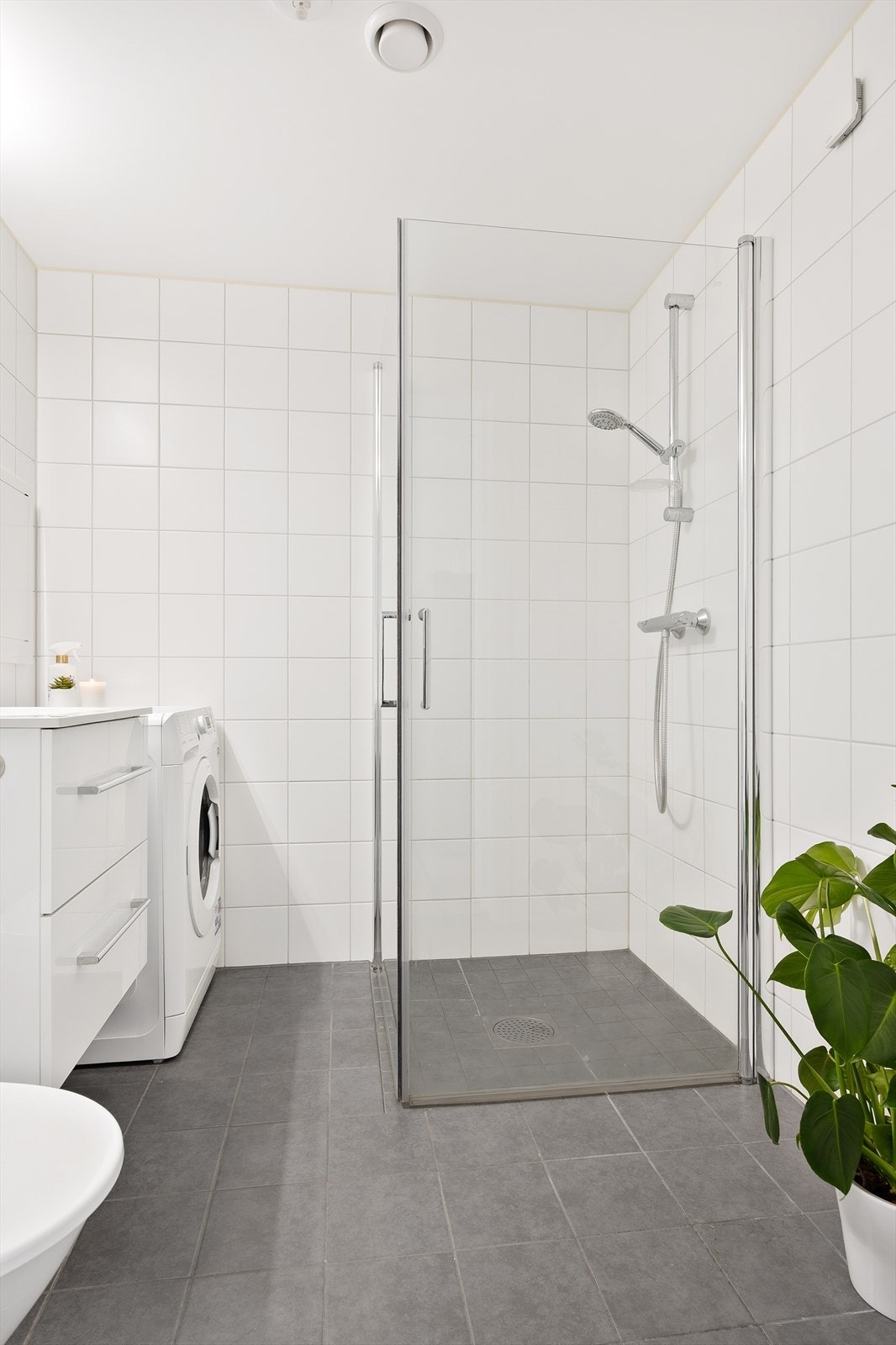 Badet er innredet med servant i baderomsinnredning, dusjhjørne med innfellbare glassvegger, toalett og opplegg for vaskemaskin. Vaskemaskinen medfølger. Galleribilde