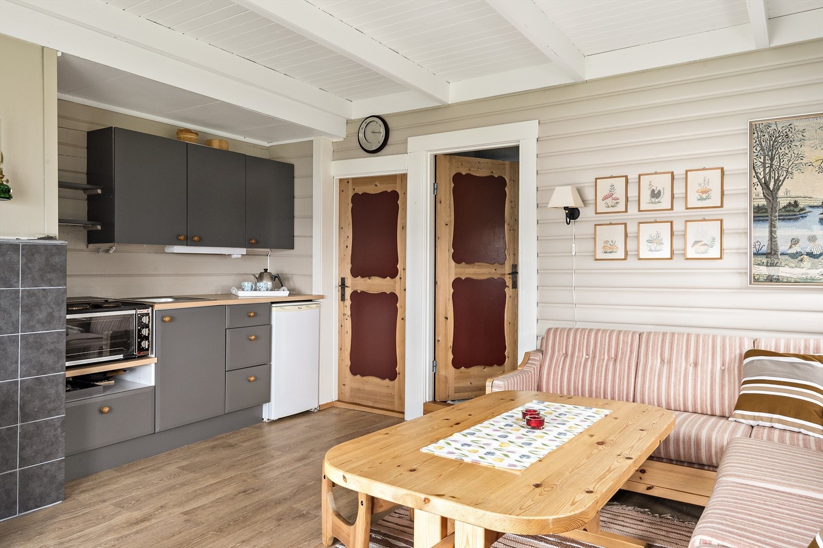 Stuen er sjarmerende med lys gråmalt rundpaneling. Gulvet er oppfrisket med et lyst gulvbelegg med eikefarget uttrykk. Galleribilde