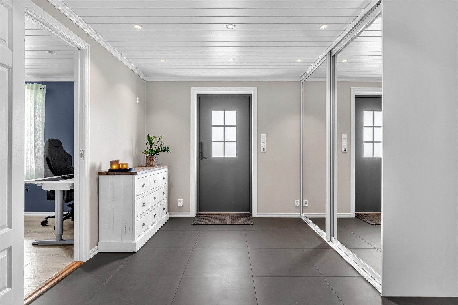 Boligen ønsker velkommen inn i en stor hall med fliser på gulv med varmekabler. Her er det stor, god skyvedørsgarderobe med speildører Galleribilde