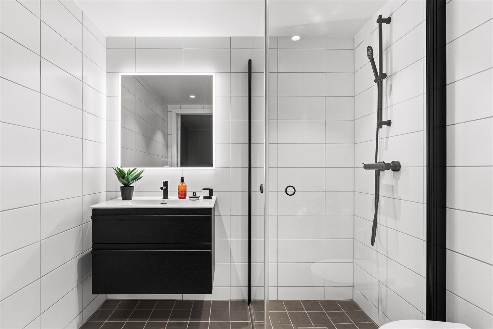 Badet er innredet med hvite veggfliser og grå gulvfliser. Galleribilde
