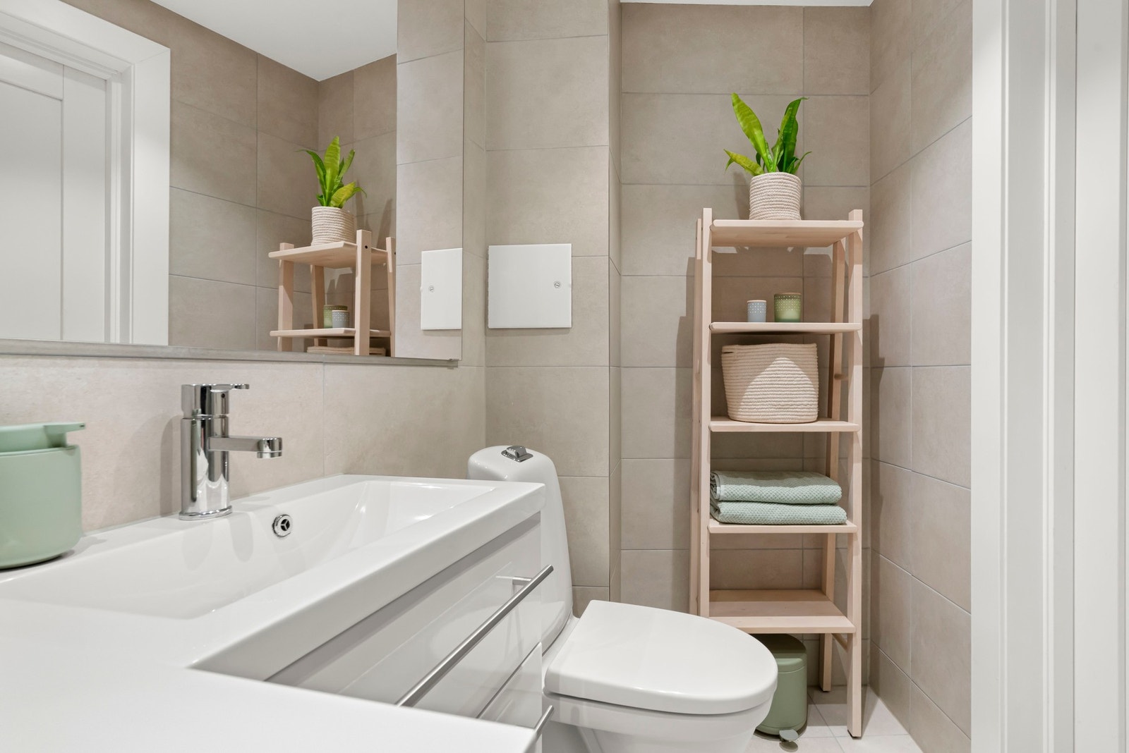 Badet har vegghengt servantinnredning med skuffer og ovenpåliggende servant, samt speil på vegg over servant. Galleribilde