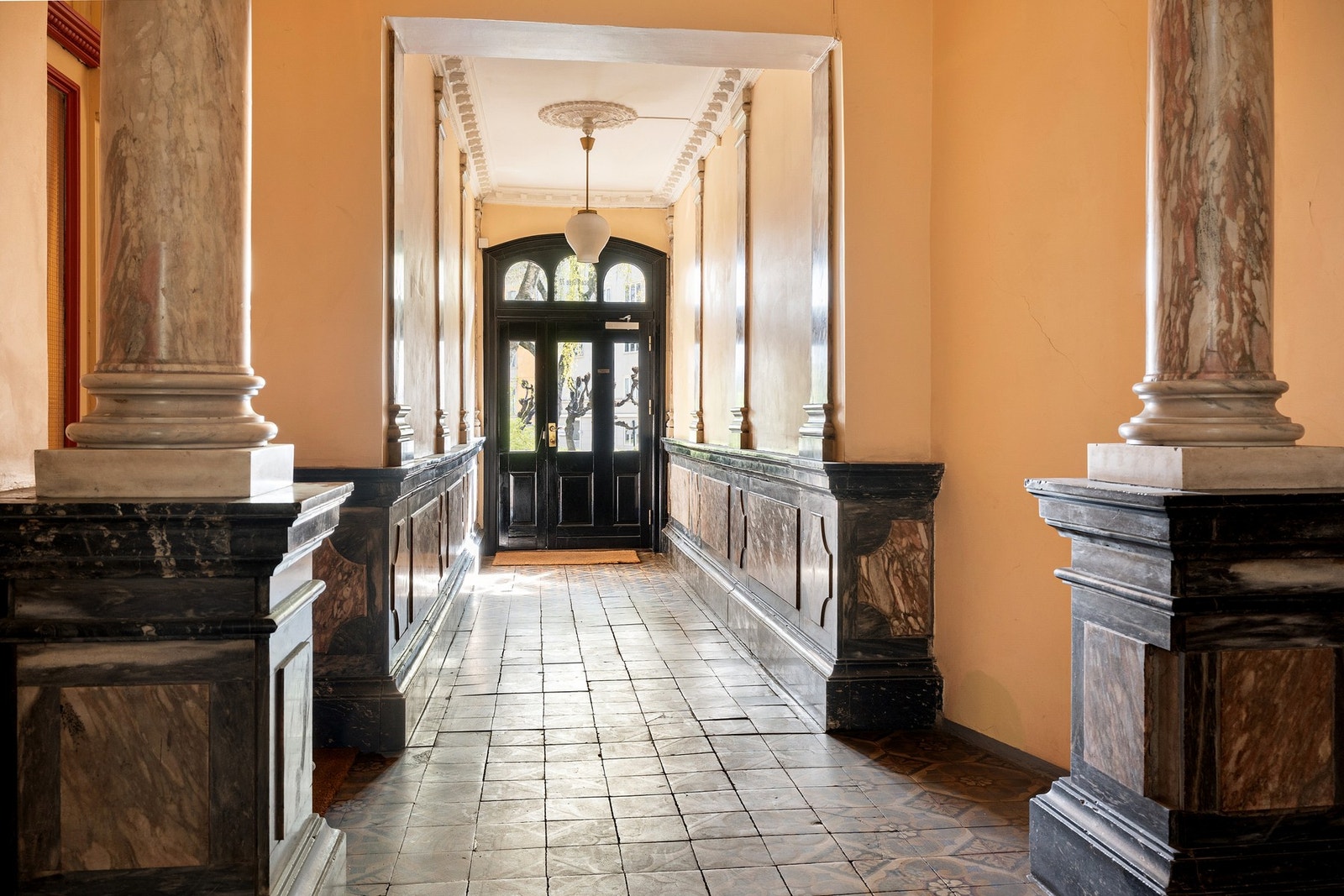 Inngangspartiet i den klassiske bygården fra 1897 er herskapelig med marmorsøyler og historiske fliser. Galleribilde