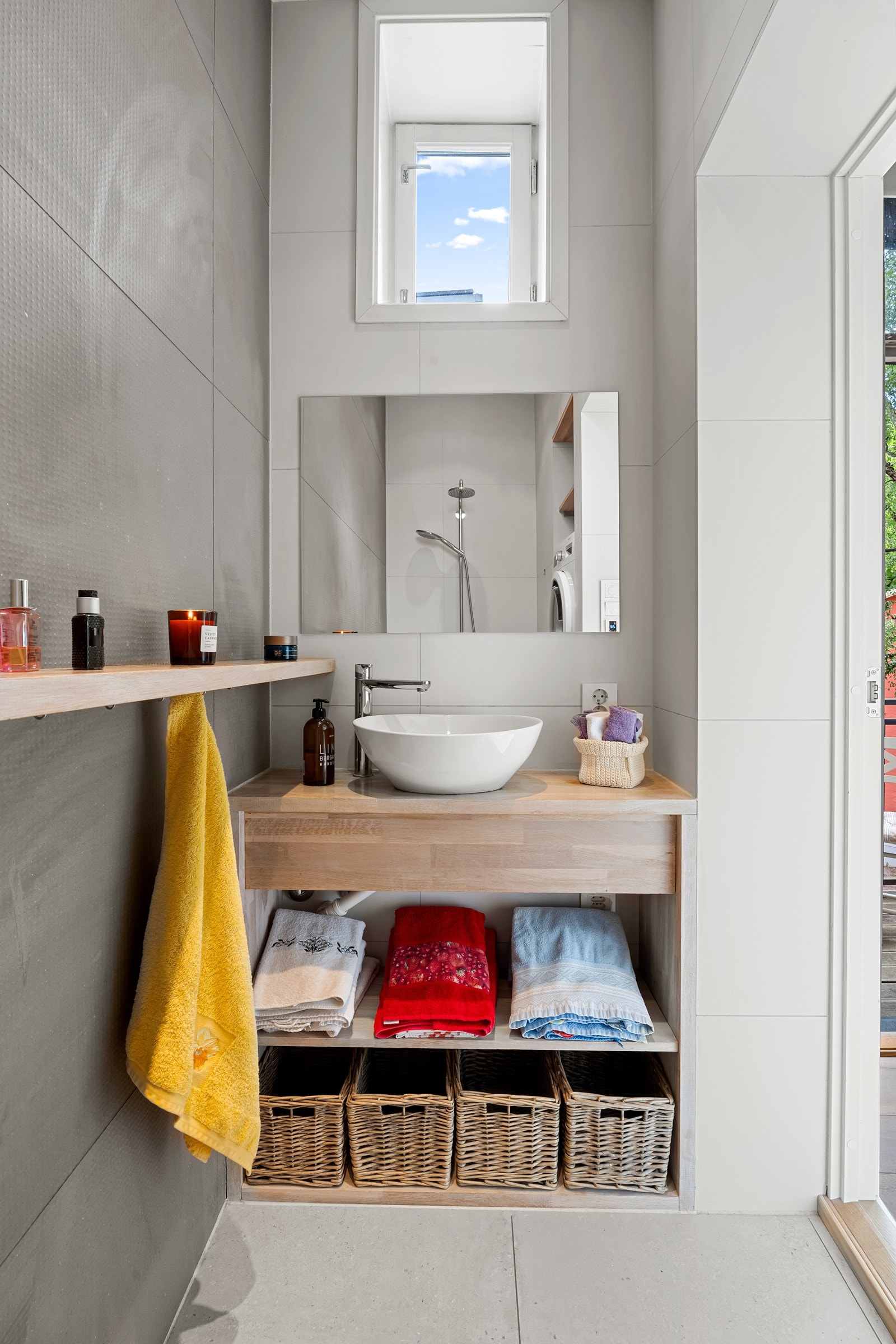 Delikat flislagt bad med plasstilpasset innredning i heltre med porselensservant. Galleribilde