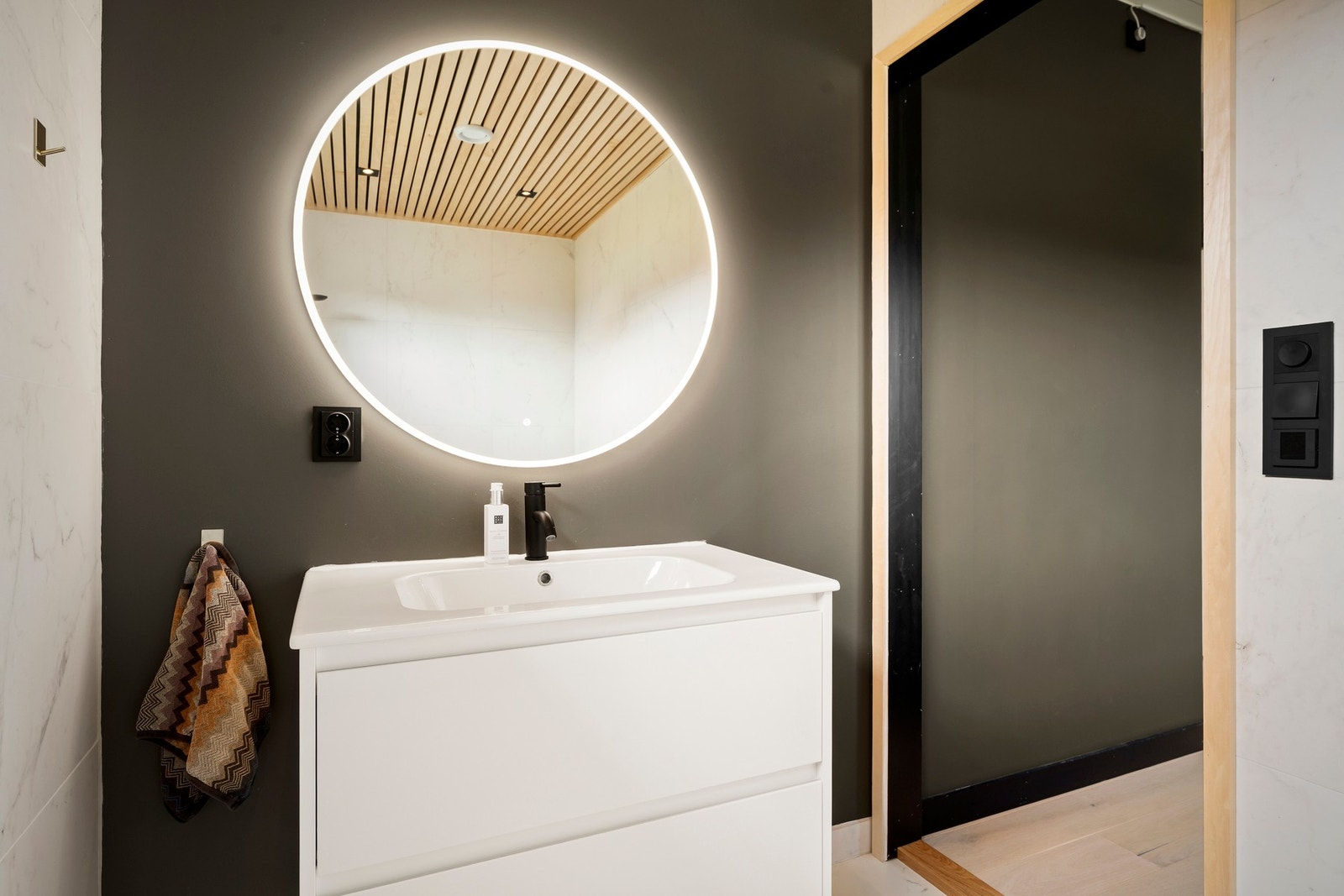 Badet er innredet med baderomsmøbel med nedfelt servant med slette, lyse fronter og overhengende speil med belysning. Galleribilde