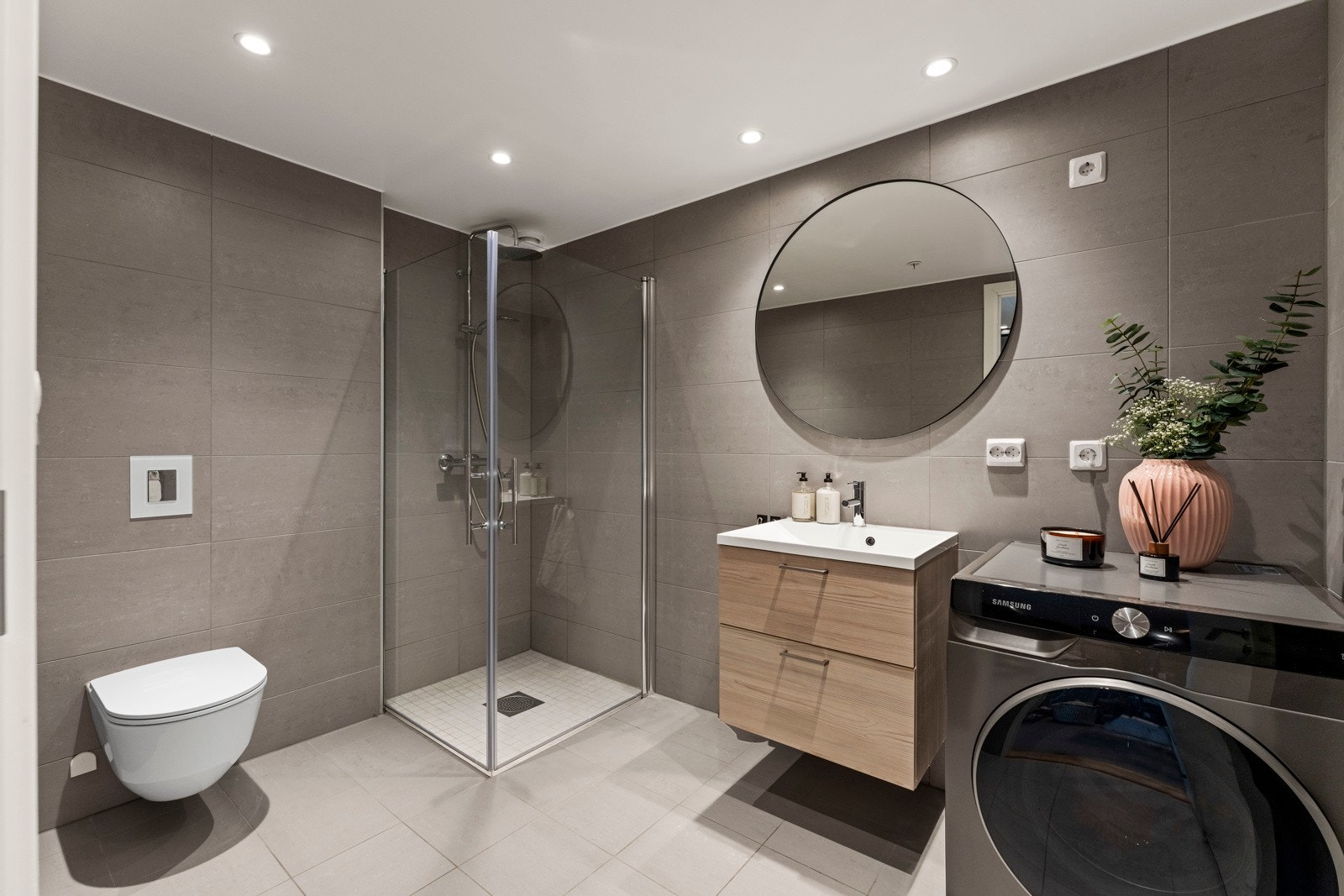 Badet er helfliset med grå gulvfliser og fliser på veggene. Varmekabler i gulvet og downlights i tak gir god komfort og belysning. Galleribilde