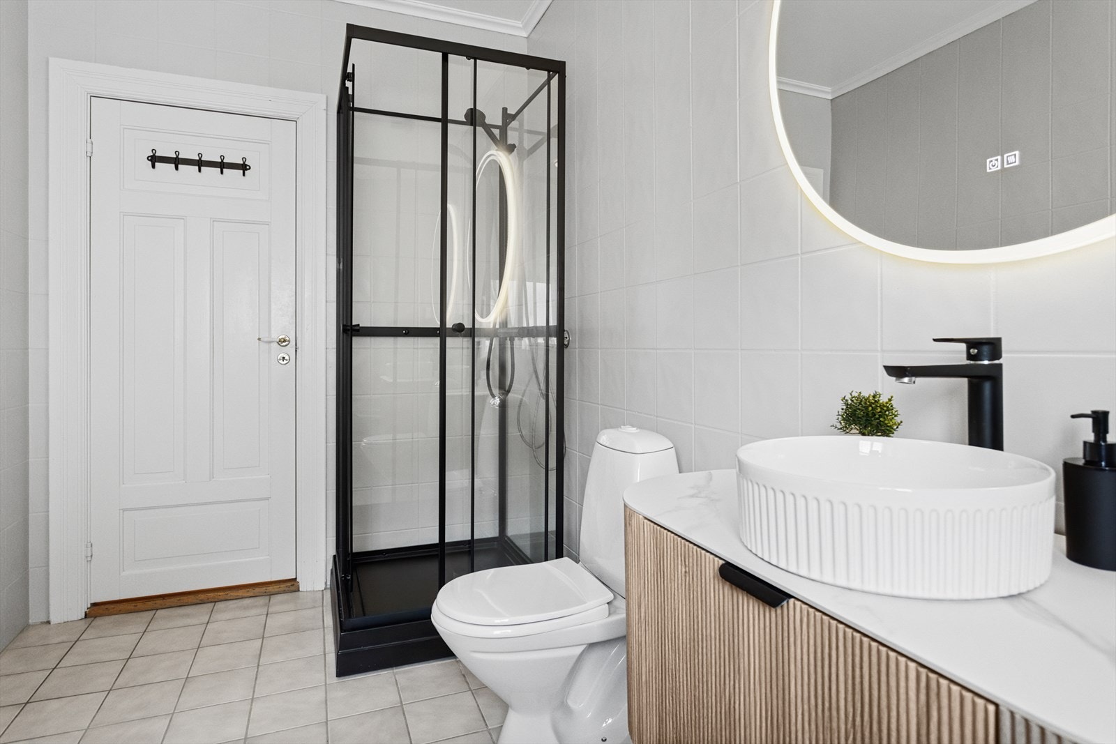 Badet er utstyrt med servantskap med profilerte fronter med laminat benkeplate med toppmontert servant. Av utstyr finnes det wc, dusjkabinett, opplegg for vaskemaskin. Gulvvarme som varmekilde. Galleribilde