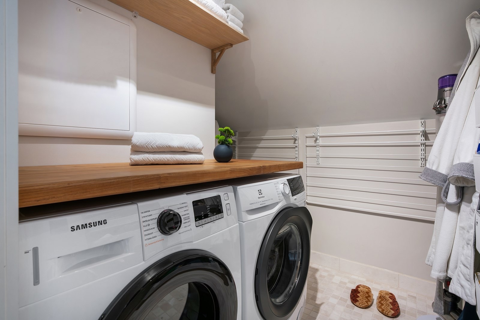 Like ved ligger et praktisk vaskerom med marmorfliser på gulv, benkeplate og opplegg for vaskemaskin, som gjør klesvasken enkel og effektiv Galleribilde